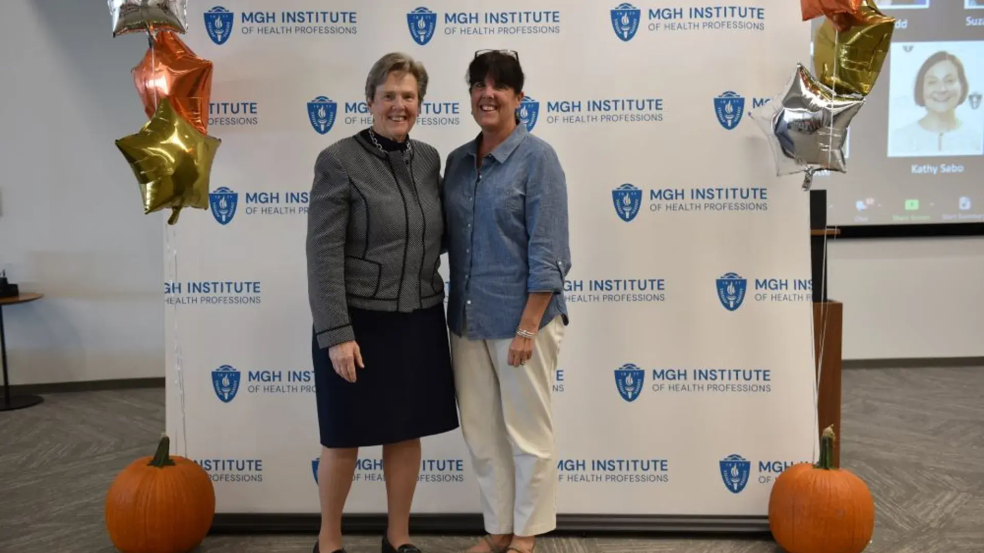 two women stand in front of MGH banner
