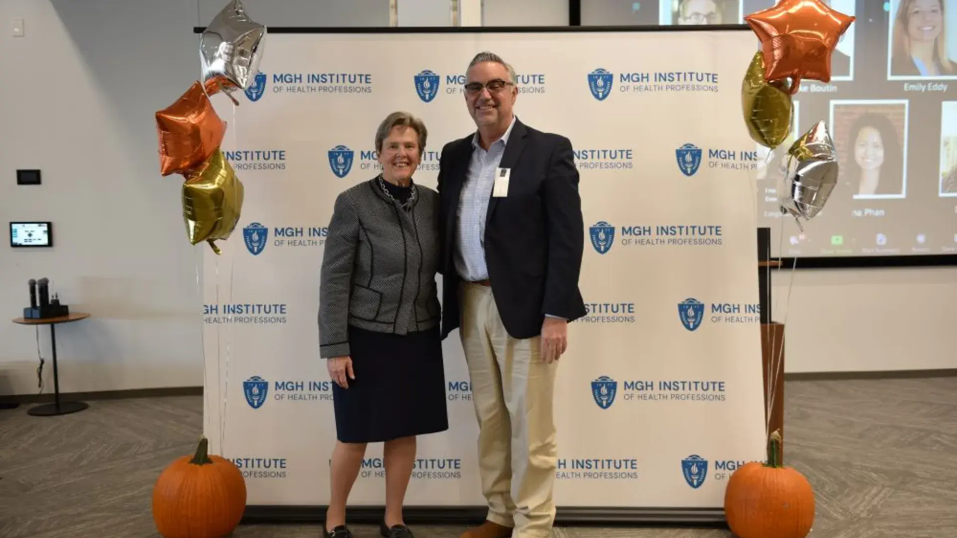 man and woman stand in front of MGH banner
