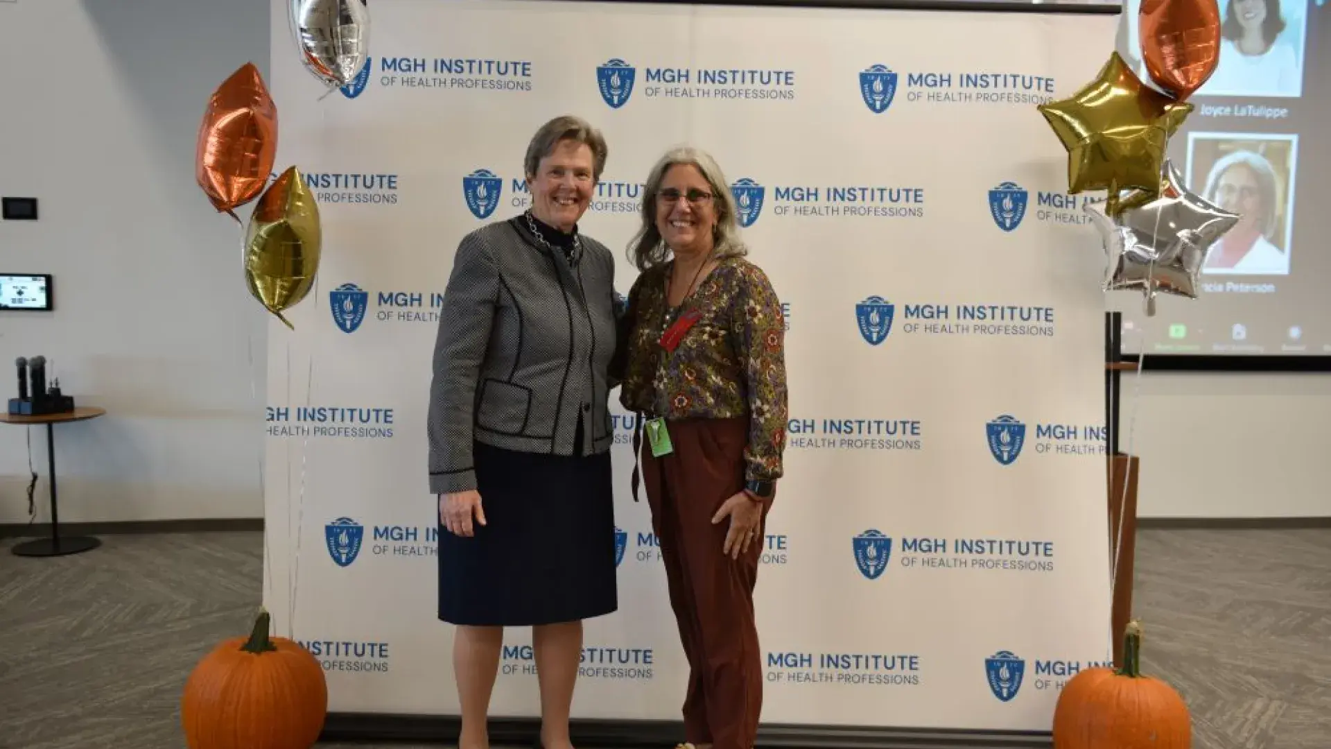 two women stand in front of MGH banner