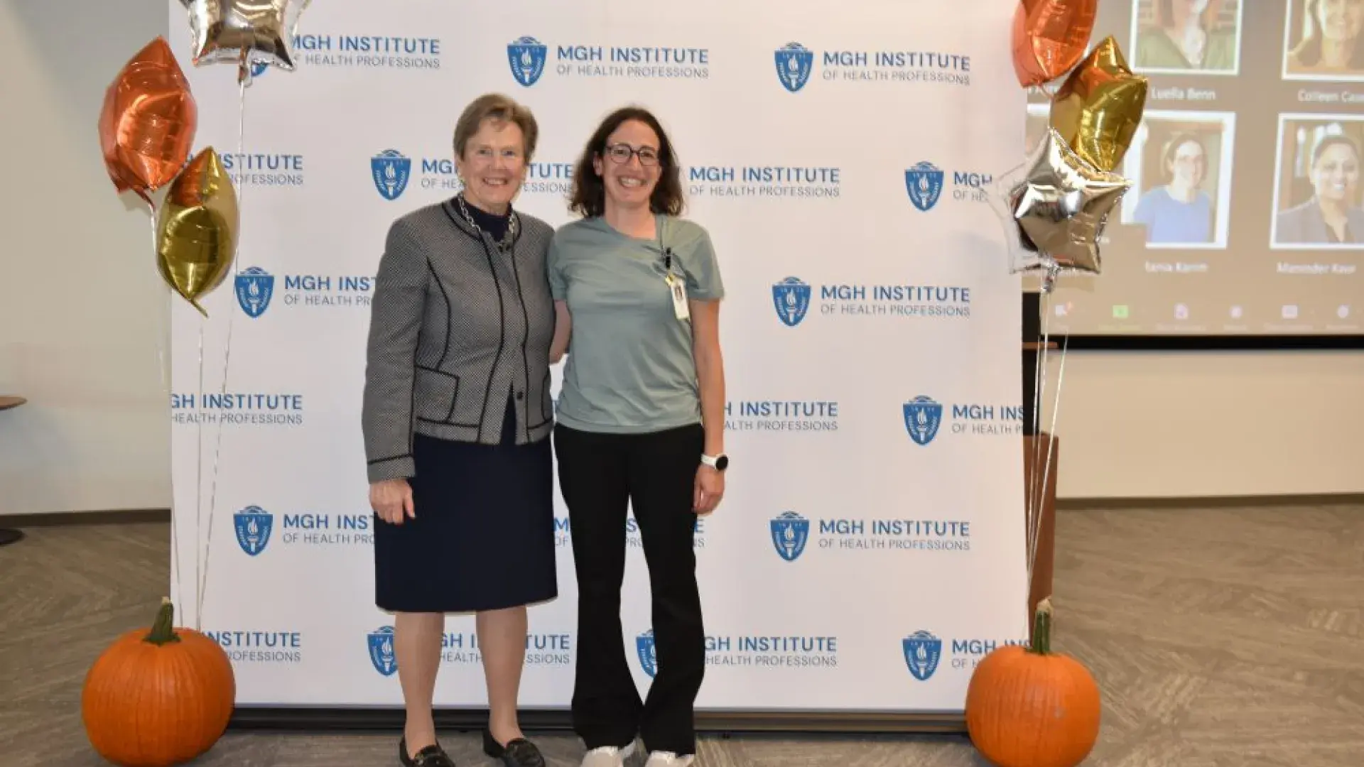 two women stand in front of MGH banner