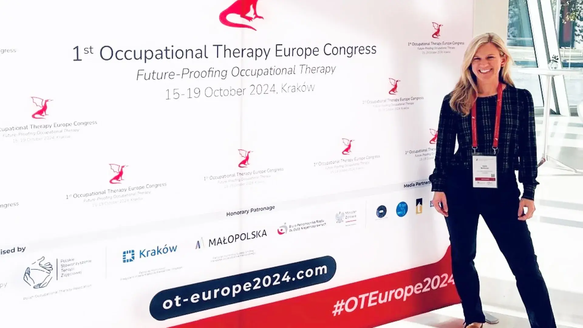 A woman stands in front of a sign for the 1st Occupational Therapy Europe Congress