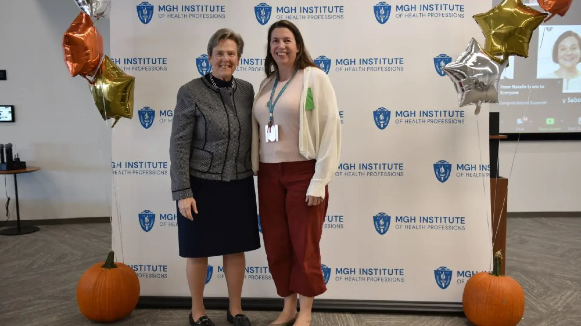 two women stand in front of MGH banner