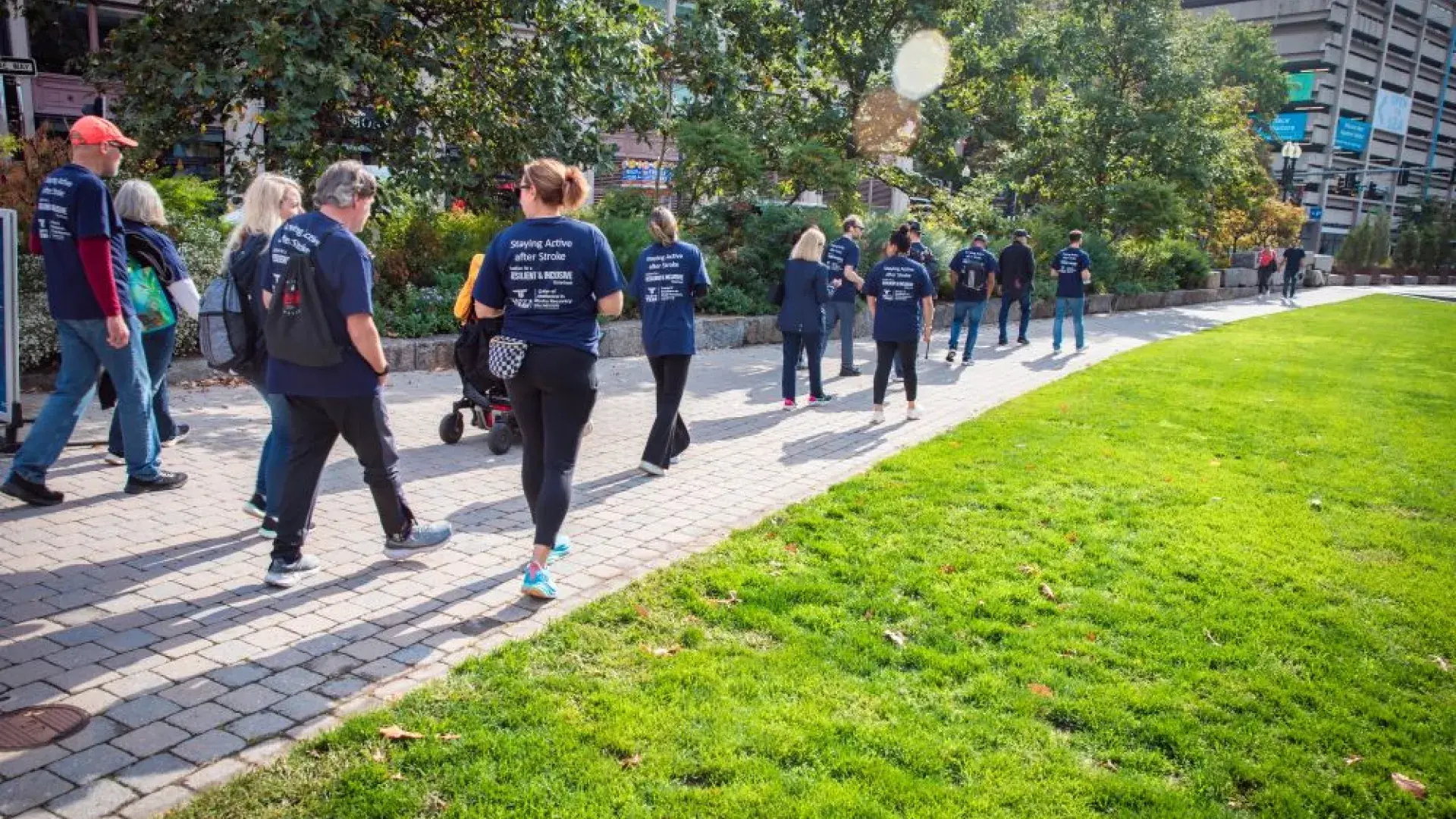 People wearing blue shirts walk along a walkway