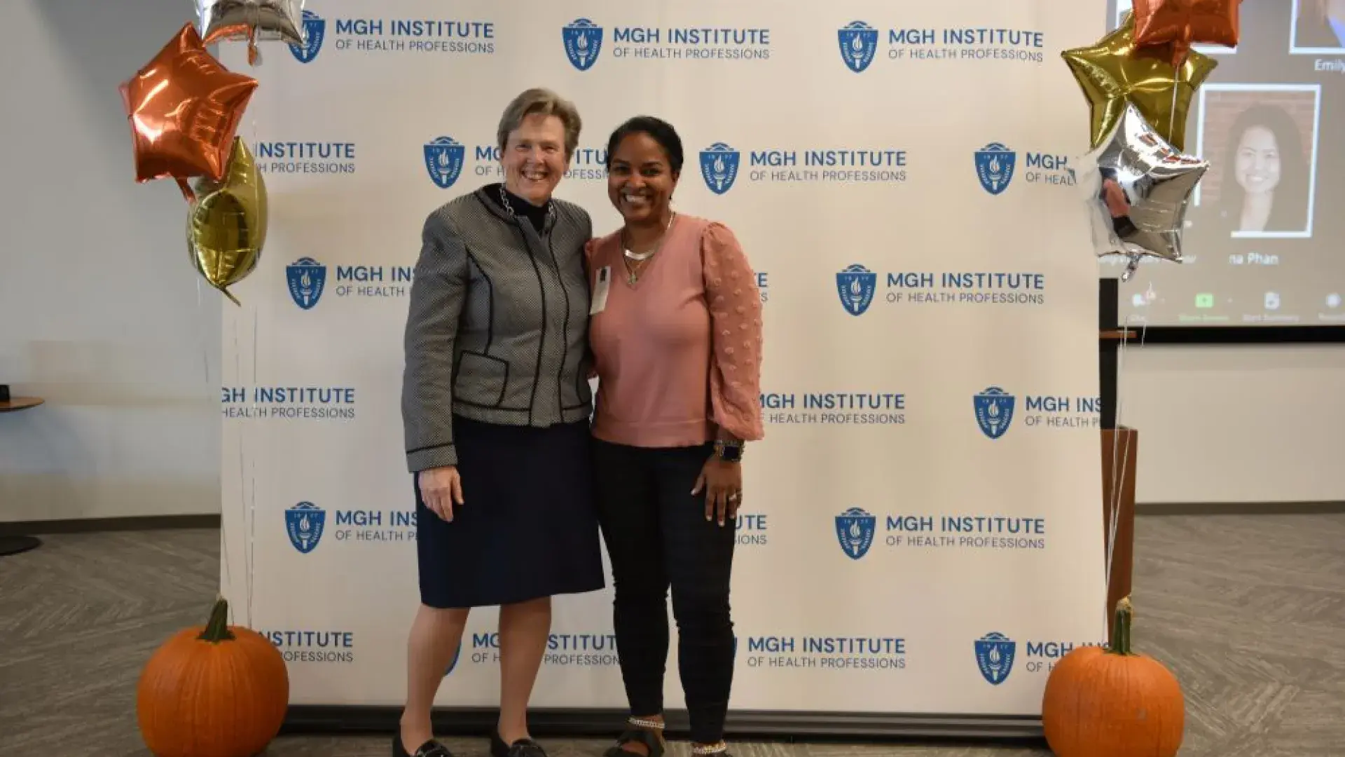 two women stand in front of MGH banner