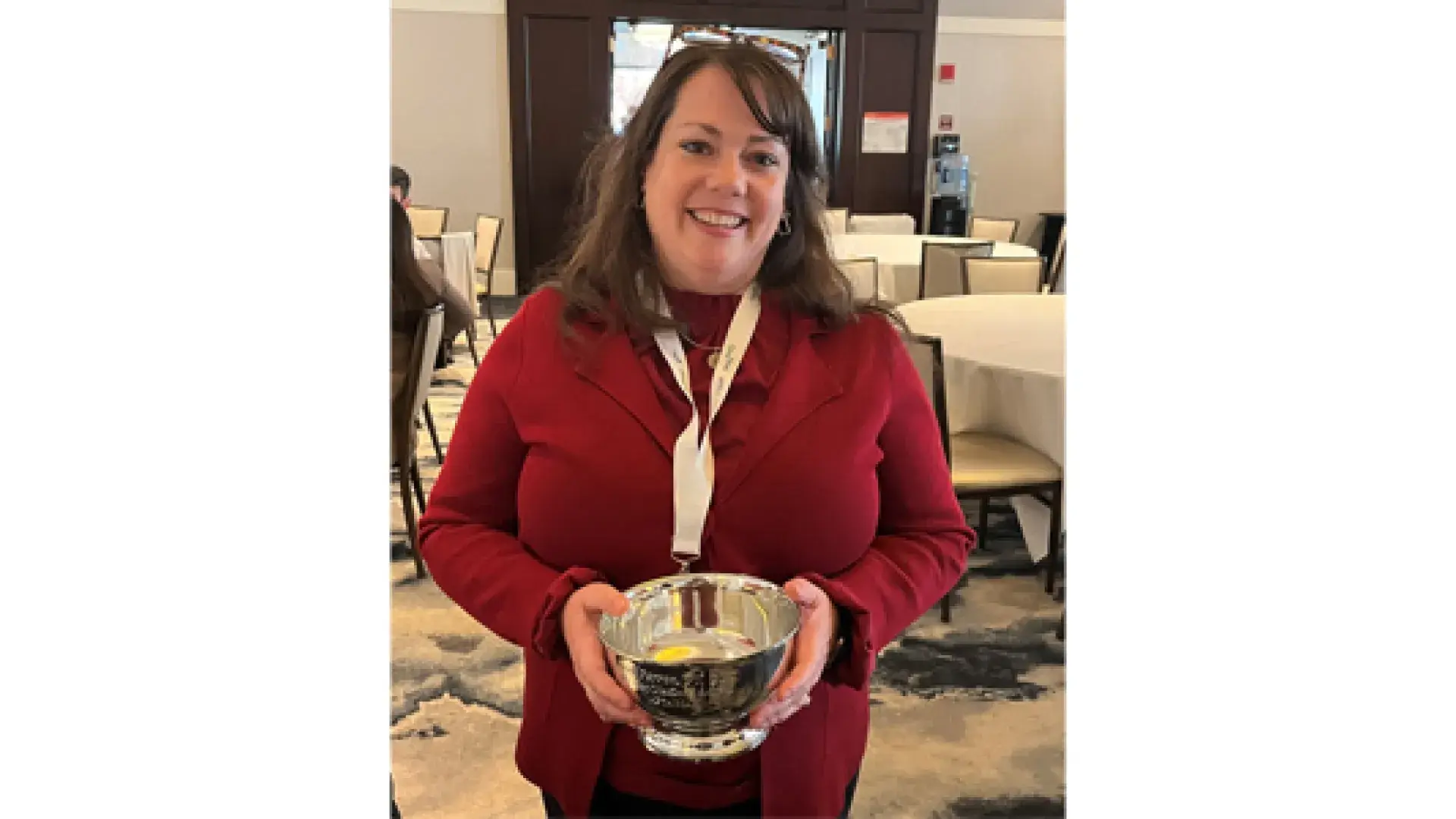 A woman stands holding a silver bowl