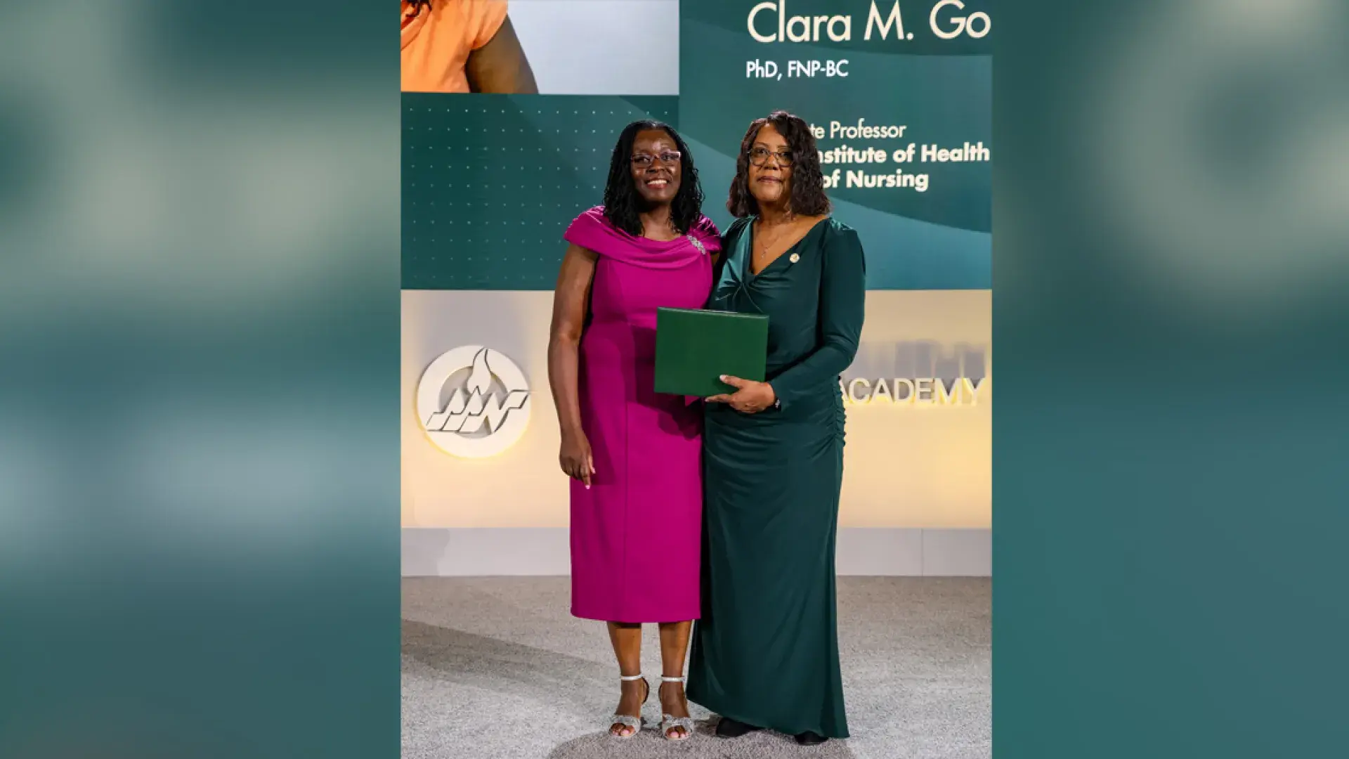 Two women pose holding a certificate in front of a screen