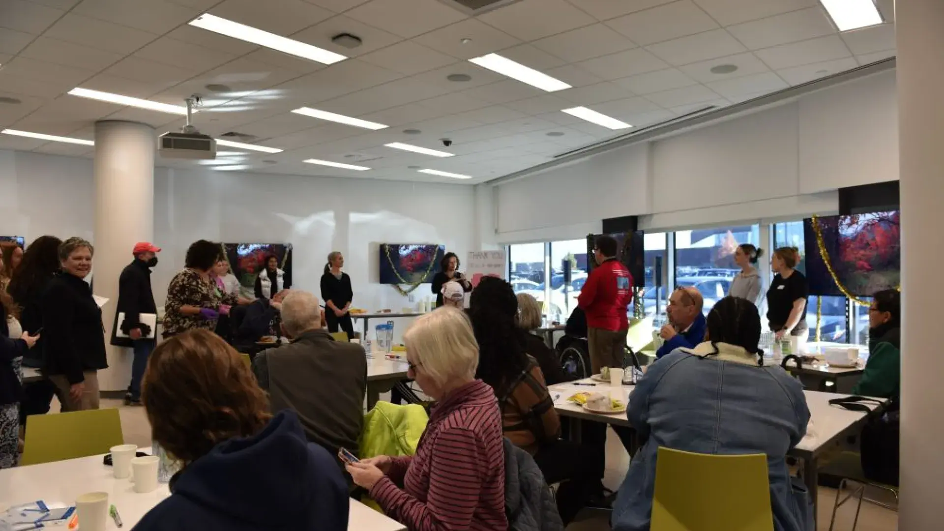 People sit at tables while a woman holding a microphone talks