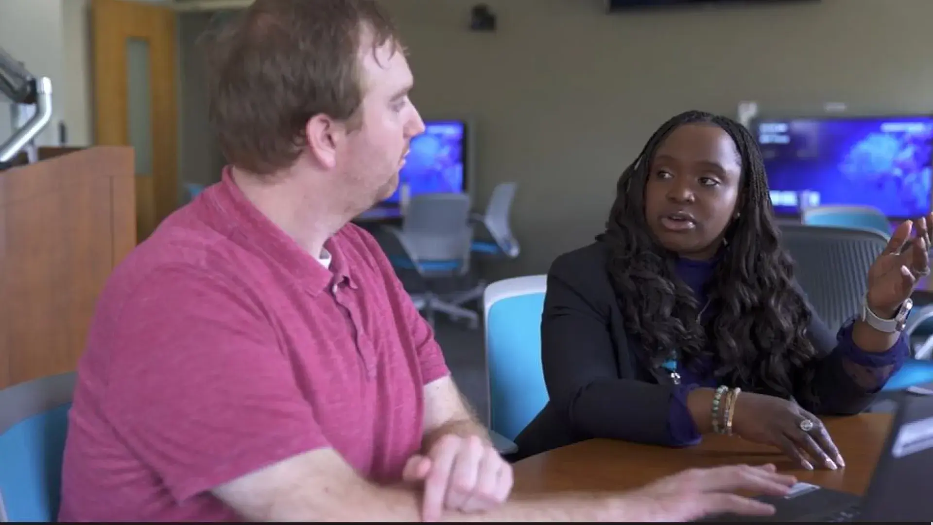 A man and woman sit next to each other at a table talking