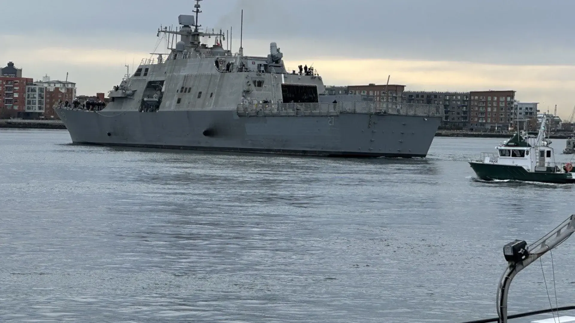 A ship heads to sea while a smaller ship trails behind
