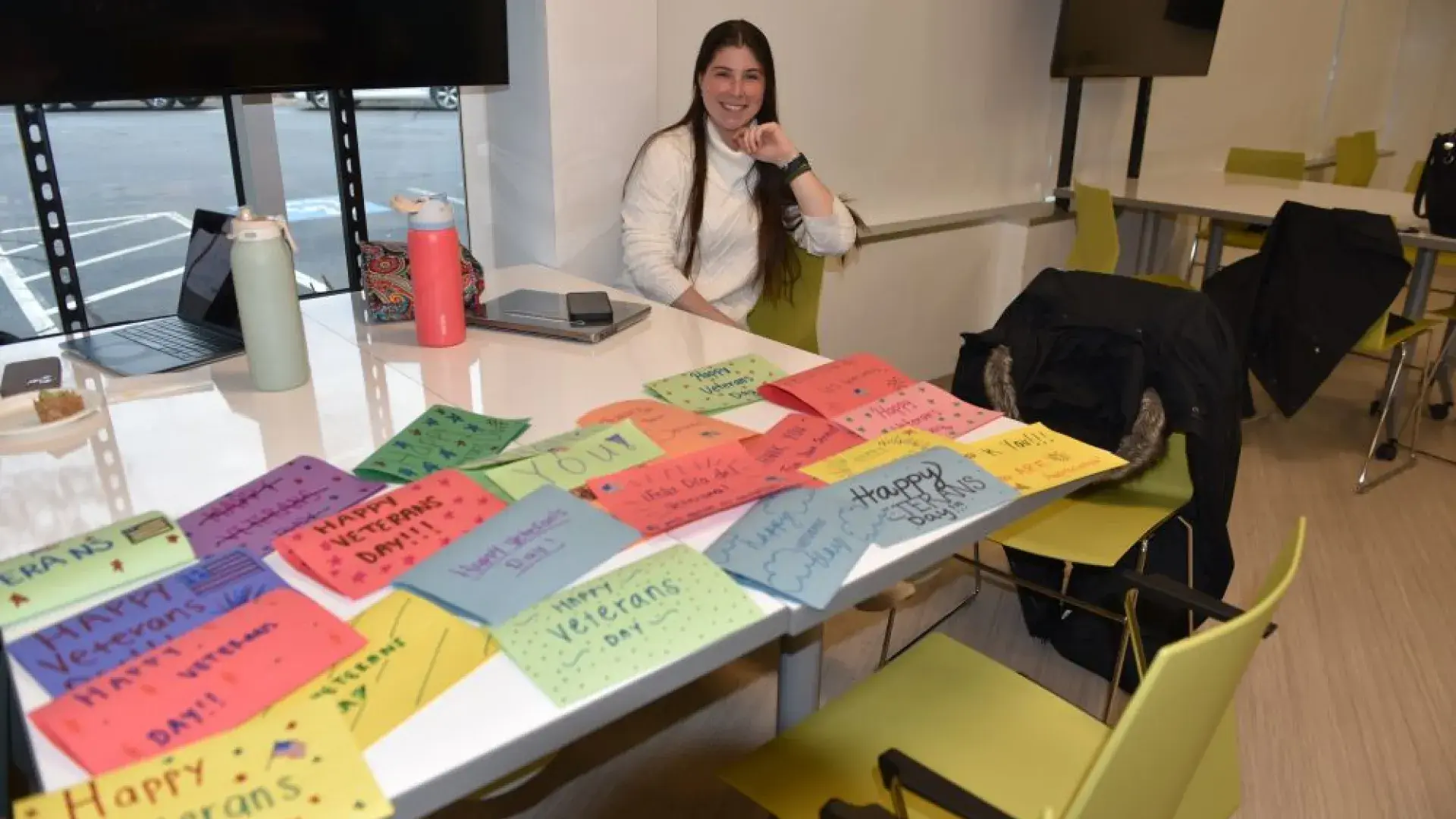 A woman sits at a table with homemade cards thanking Veterans