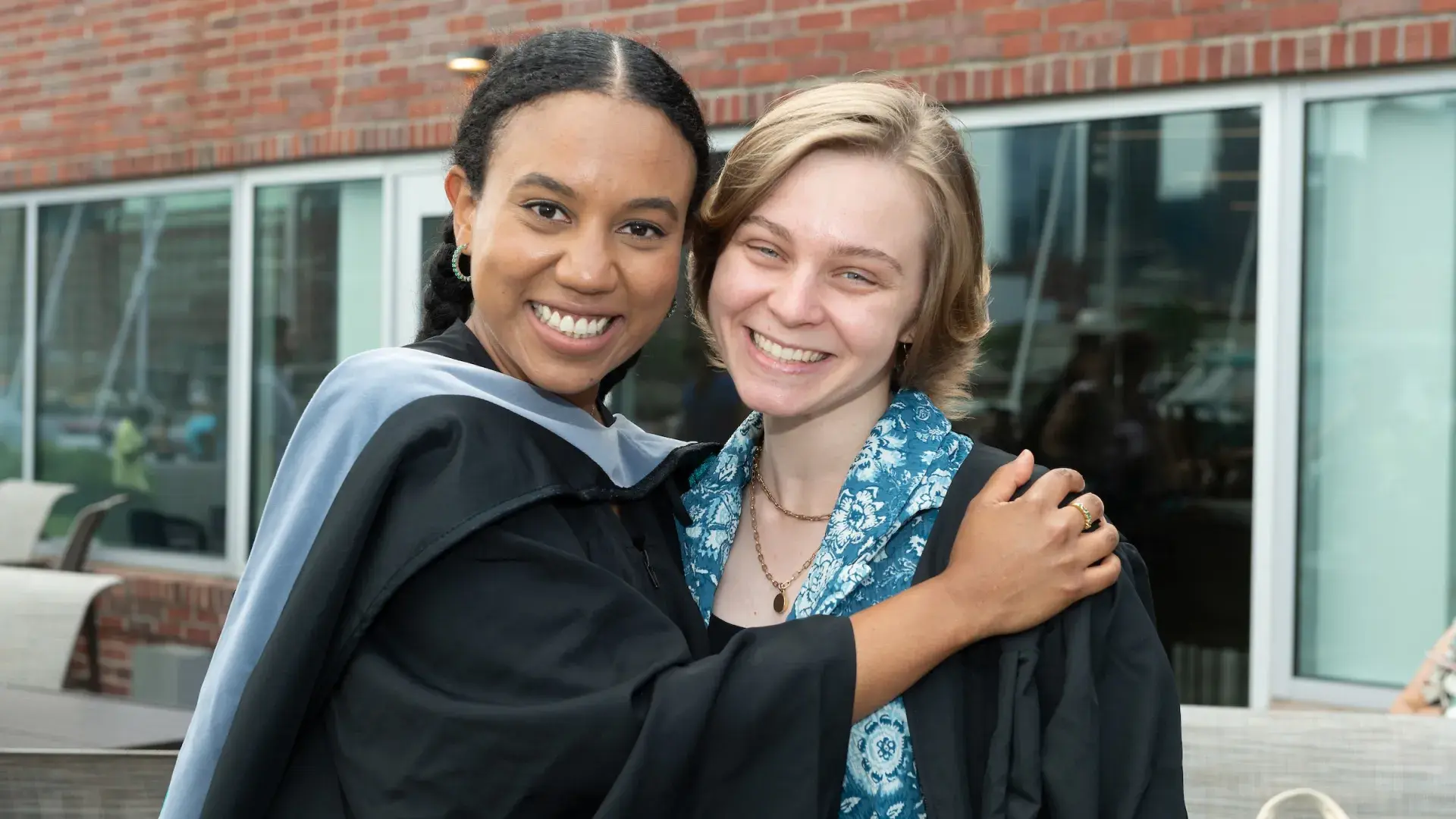women hugging with graduation robes on
