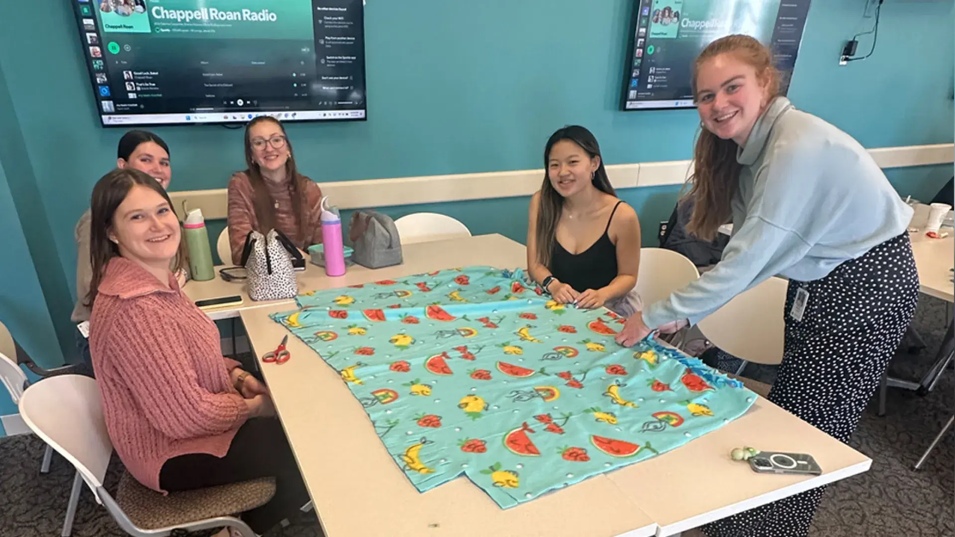 Students around table making fleece blanket 