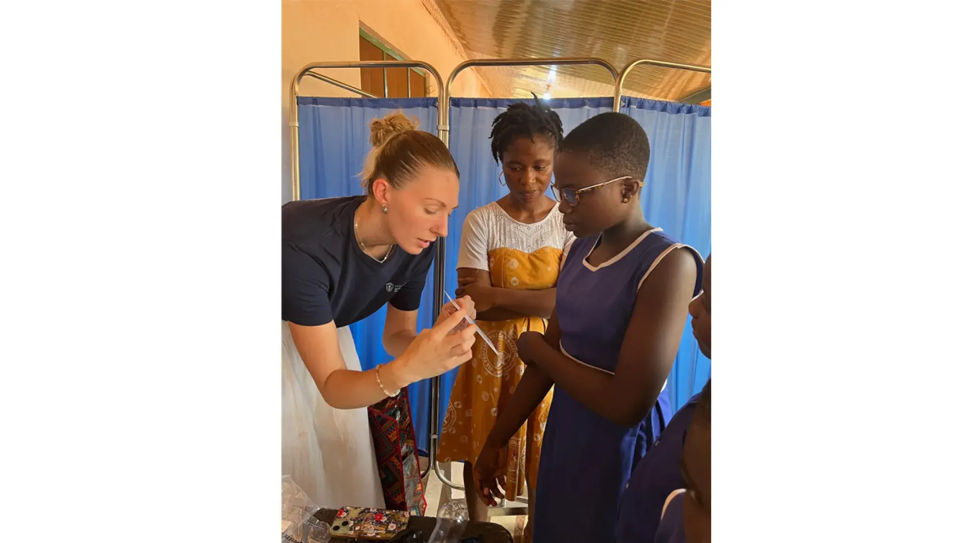 A woman holds a card for a child to look at while another woman looks on