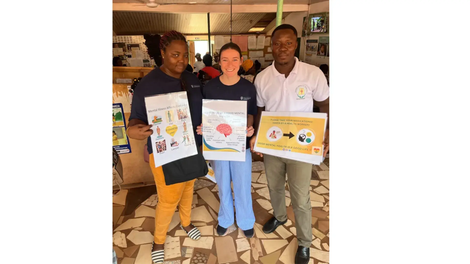 Three people stand holding posters with information about mental health