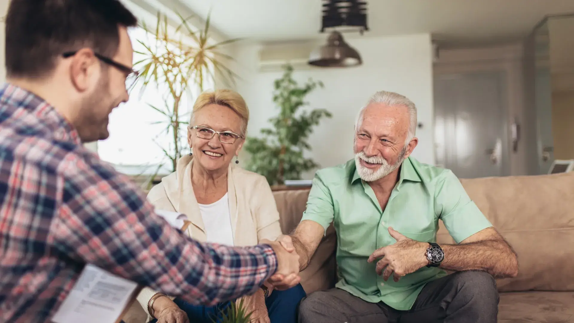 man and woman who look retirement age shake hands with a younger man