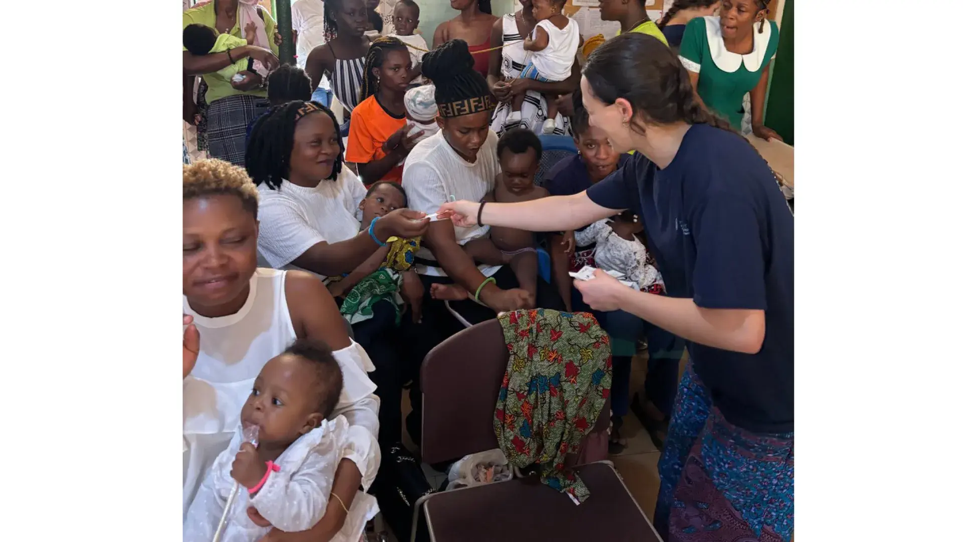 A woman hands something to a woman holding a child