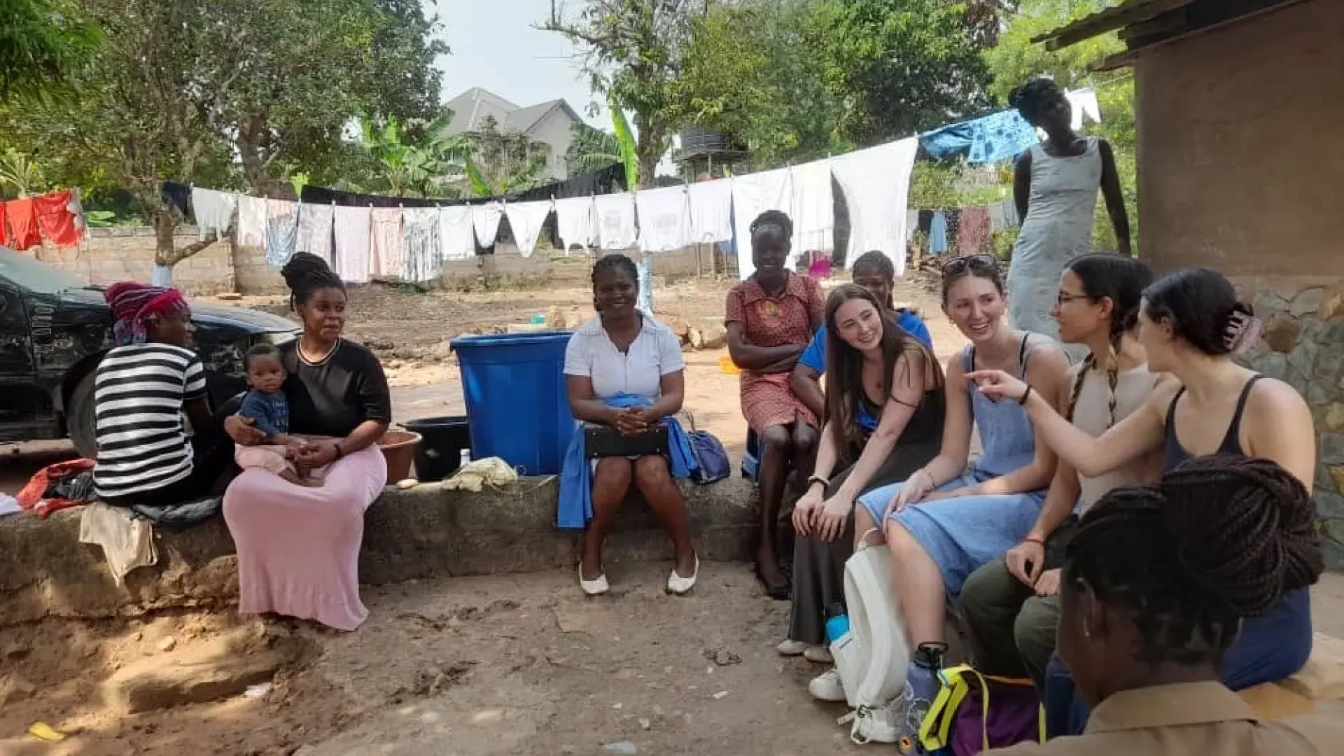 A group of people sit around on a low rock wall