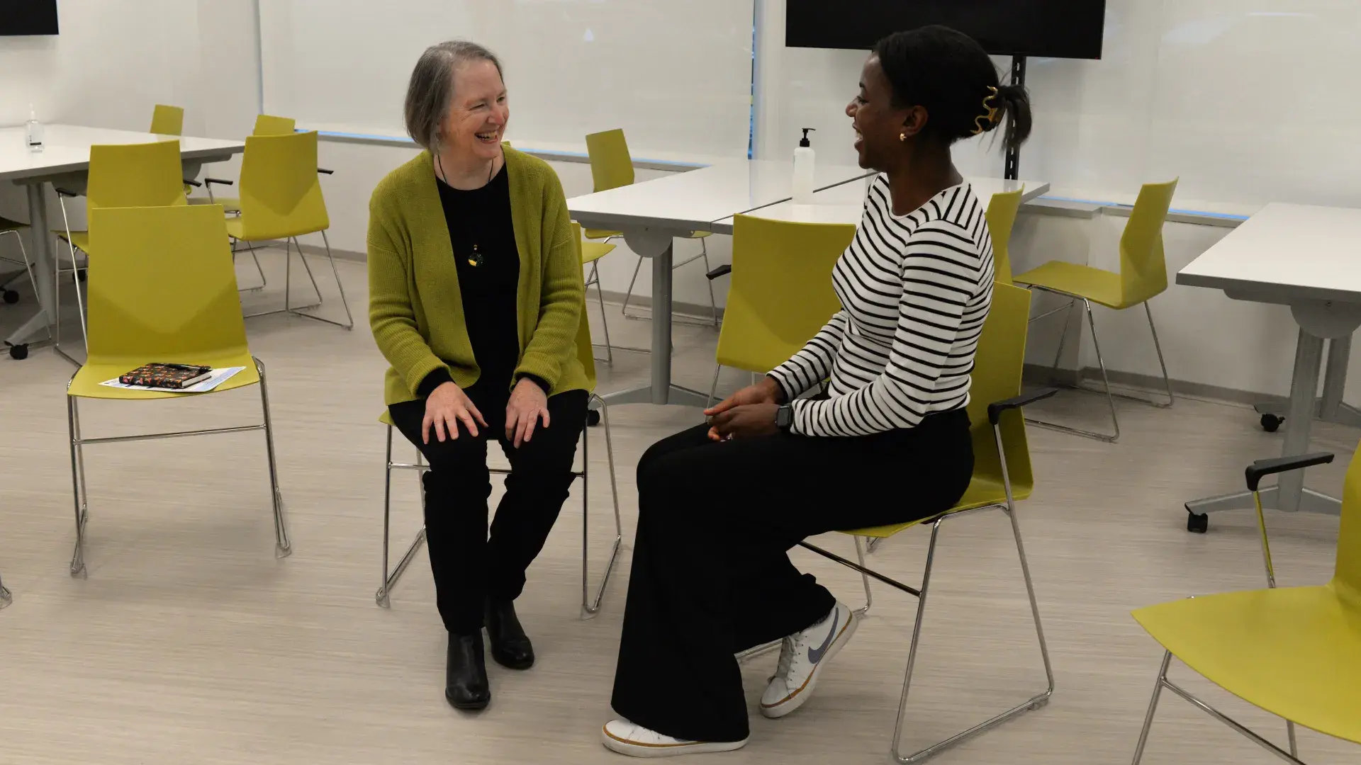 two women sitting in chairs and smiling 