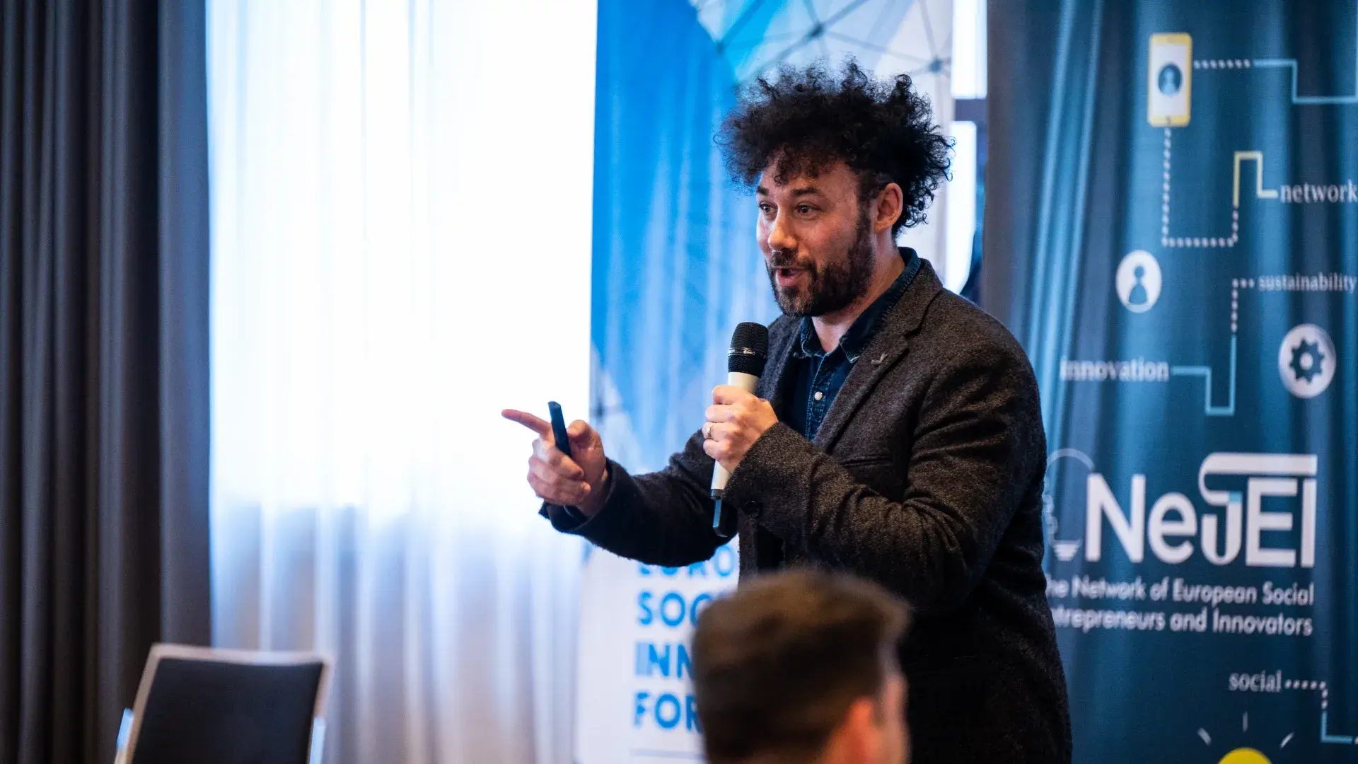 Man speaking to crowd with microphone 