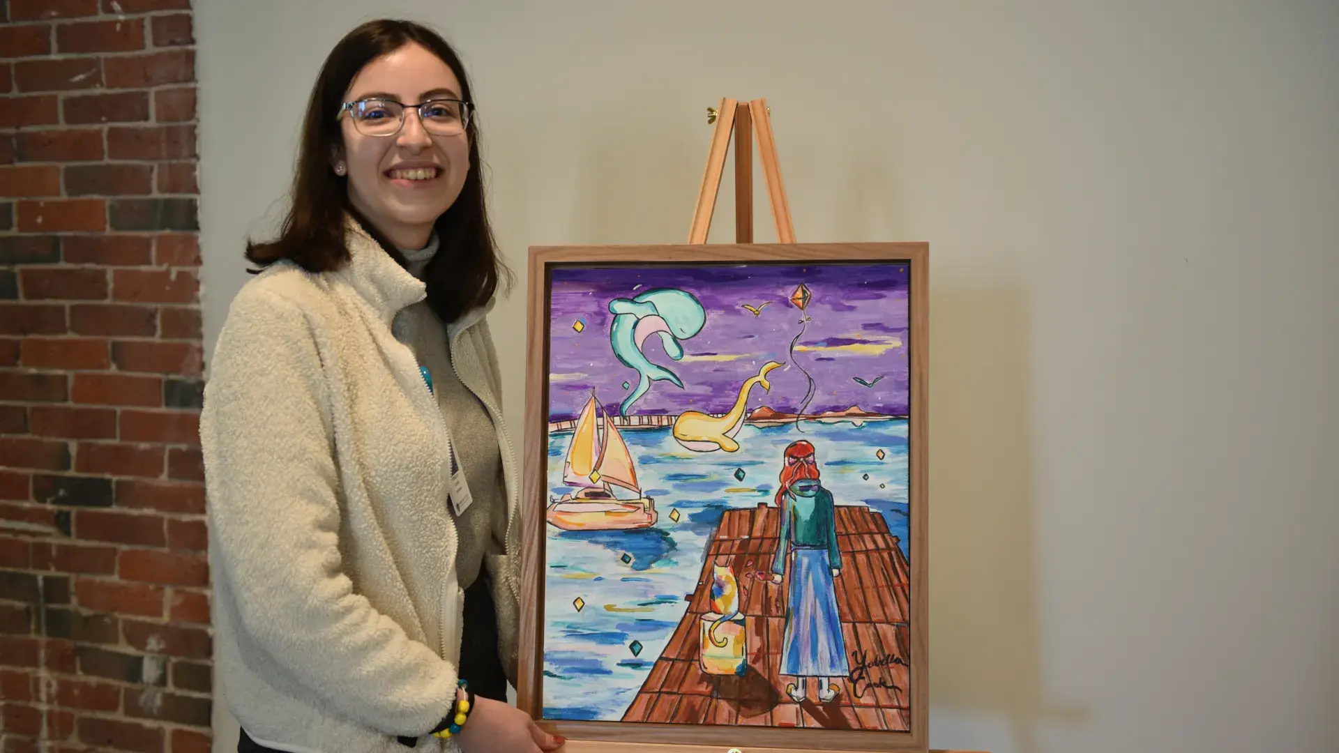 A woman stands next to a painting on a stand