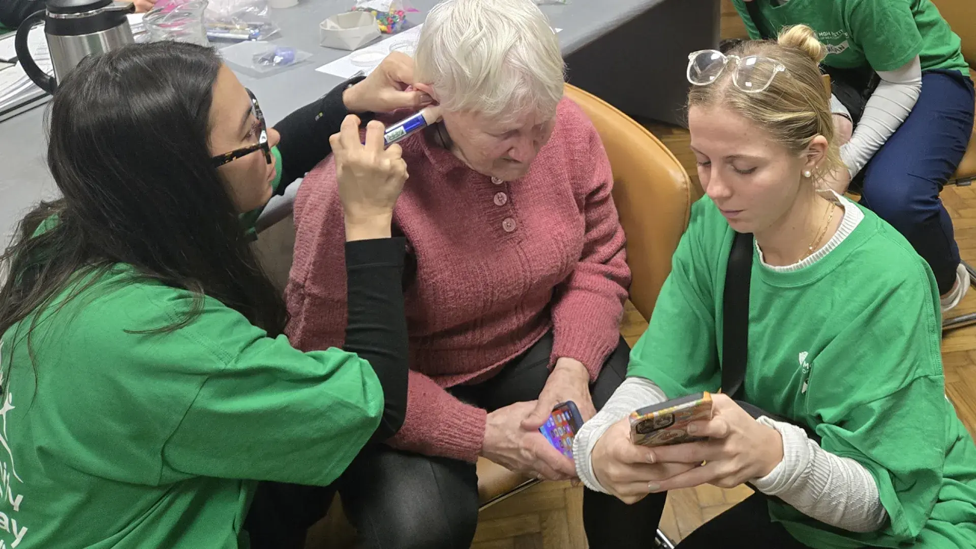 two students making ear mold with patient 