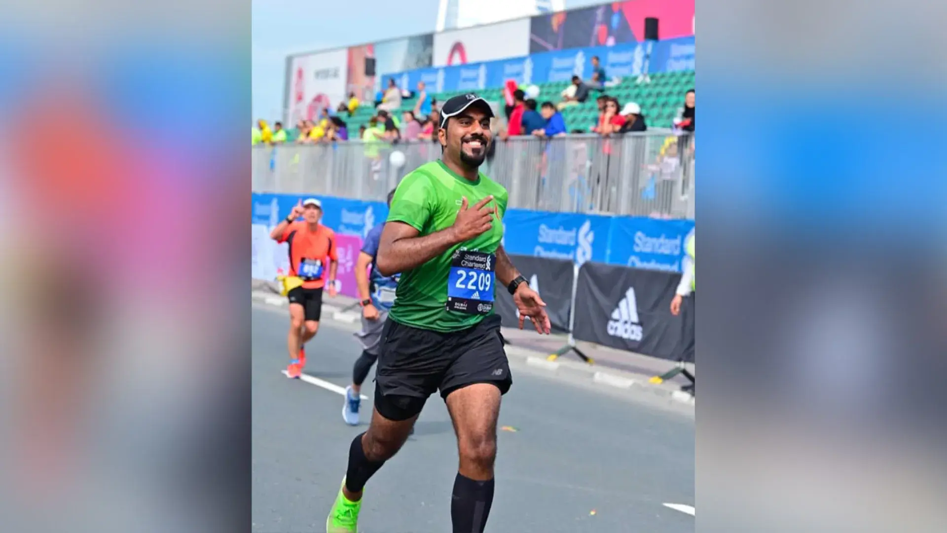 A man running wearing a green running top and a bib number