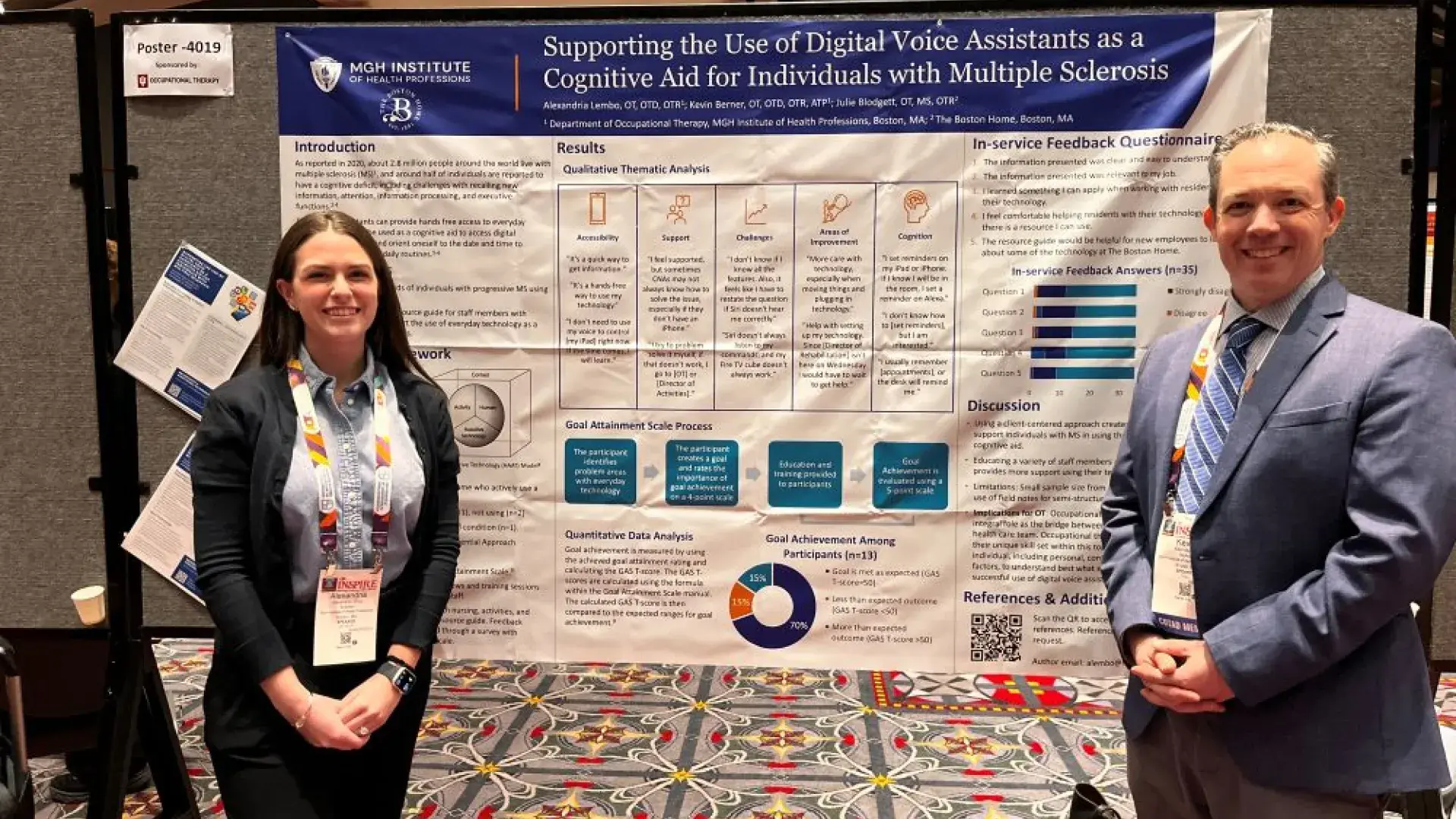 A woman and a man stand on either side of a poster 