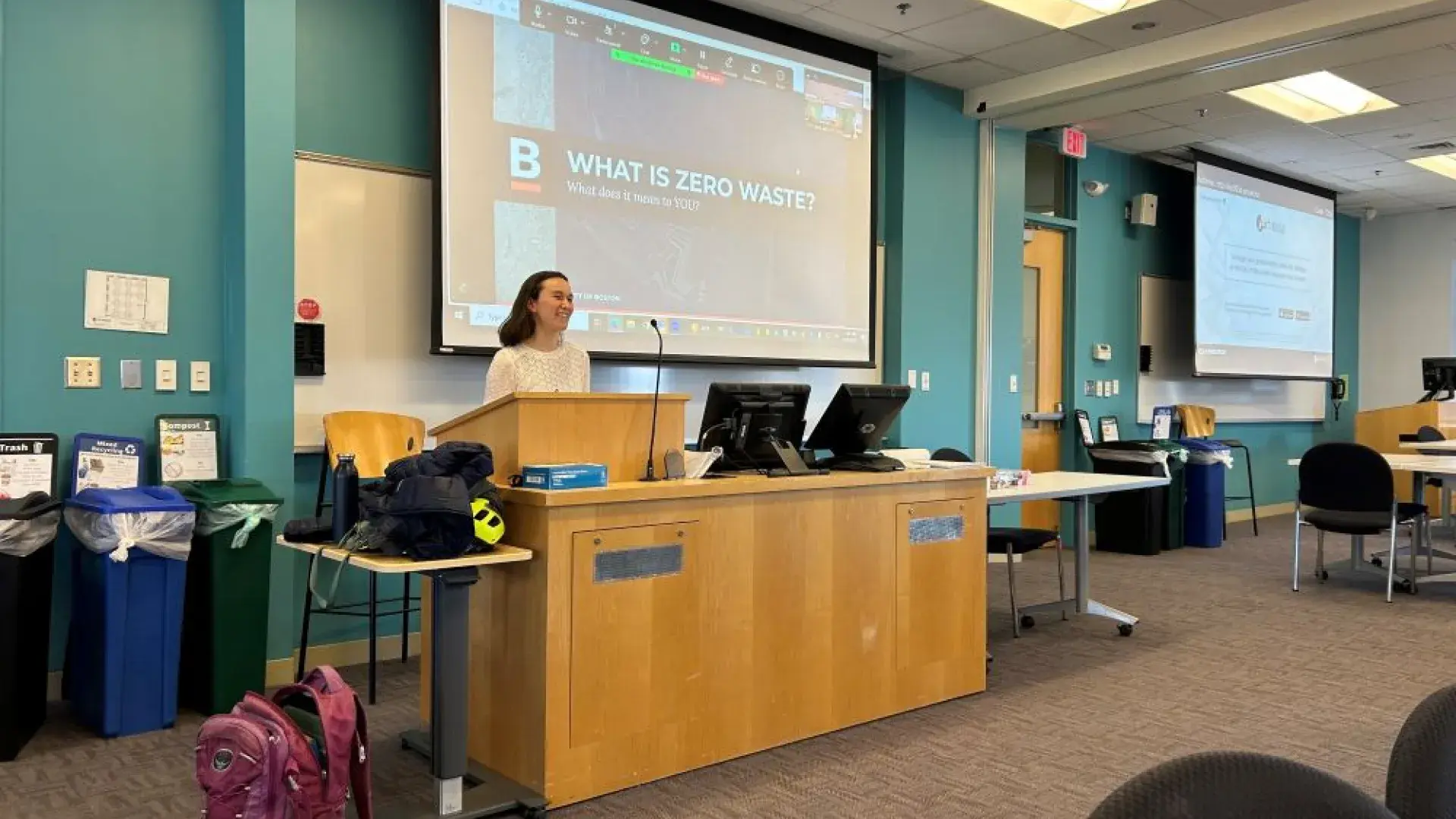 A woman stands behind a podium in front of a classroom