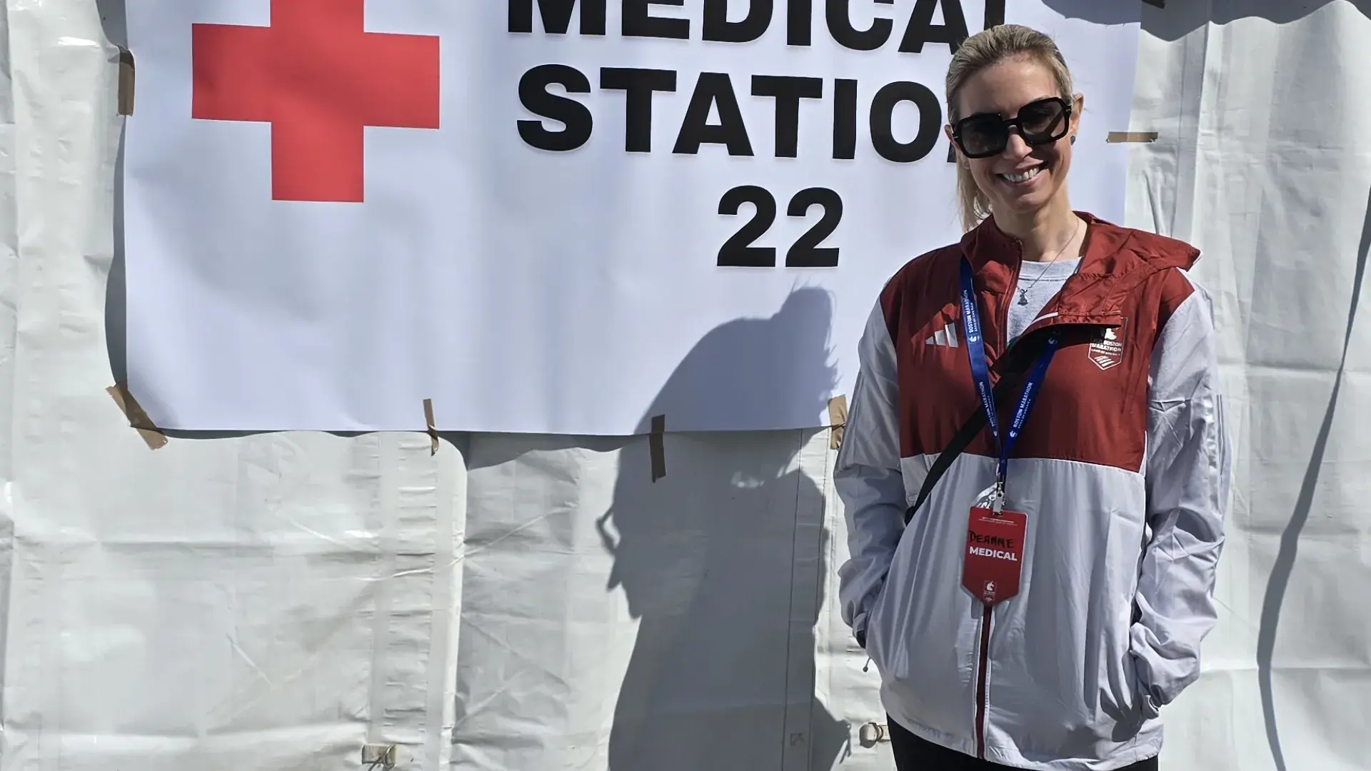 A woman stands in front of a tent with a banner than says medical station 22