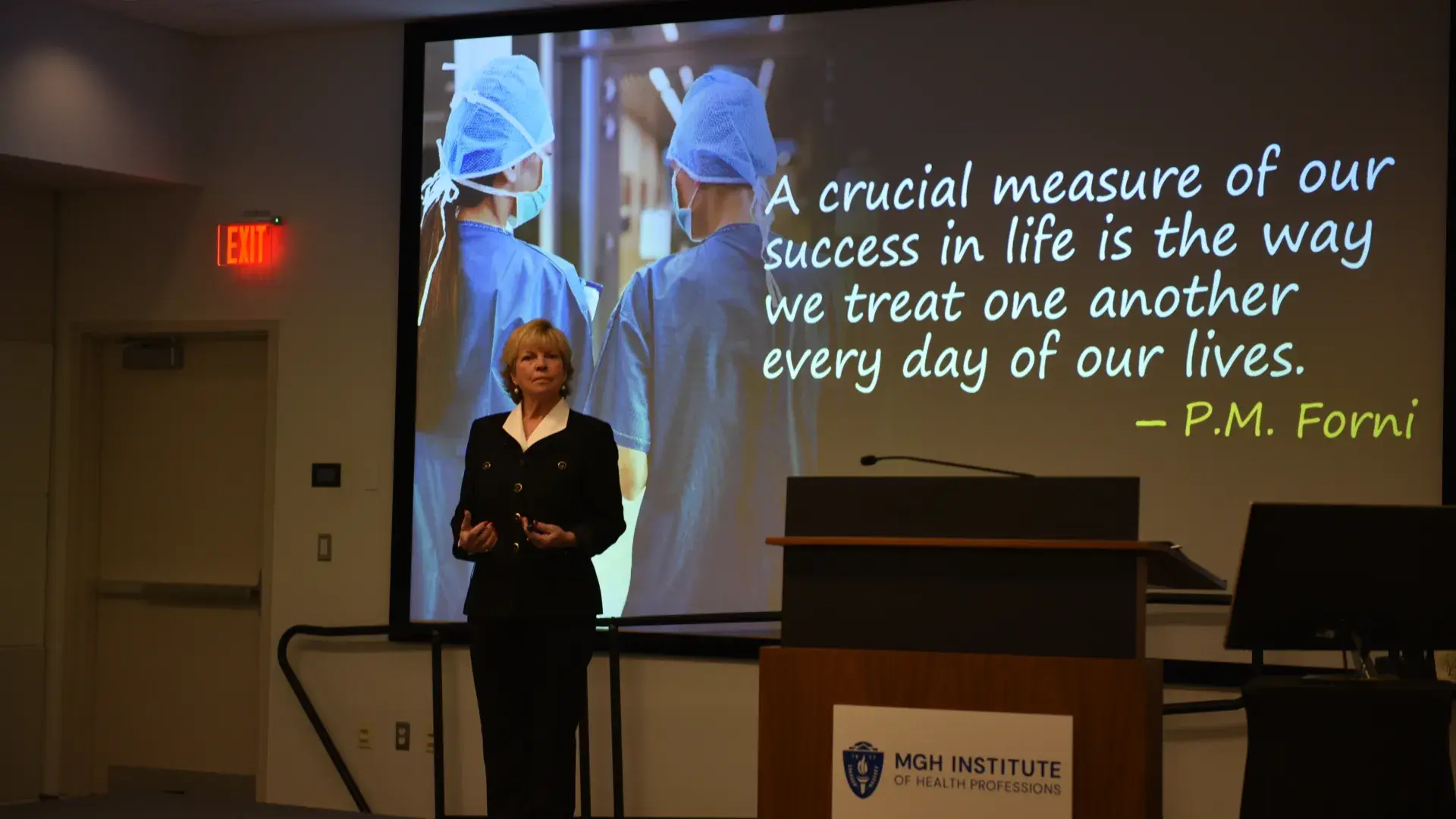 A woman stands in front of a screen with a quote