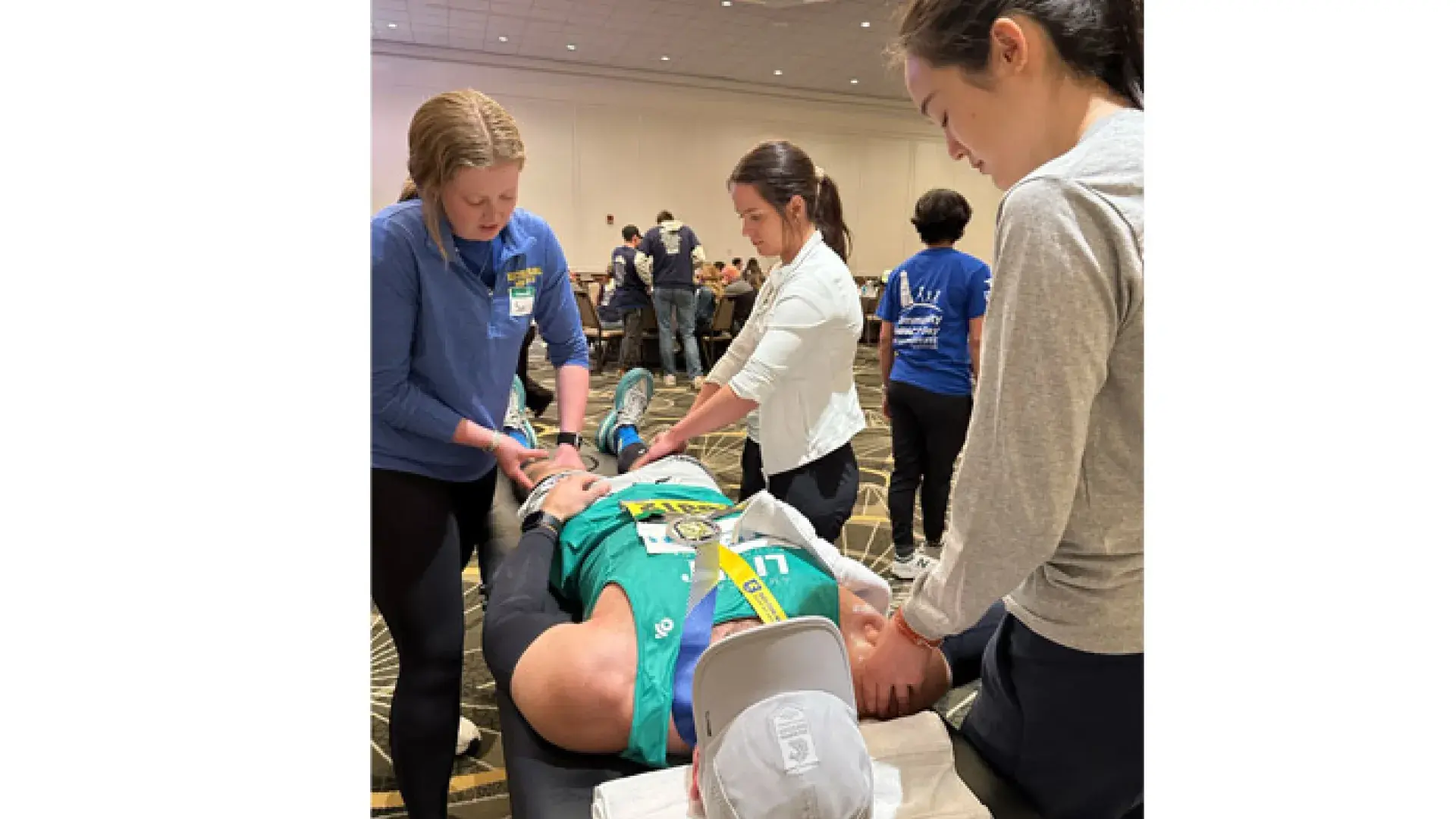 Three people massage someone lying on a table wearing running attire