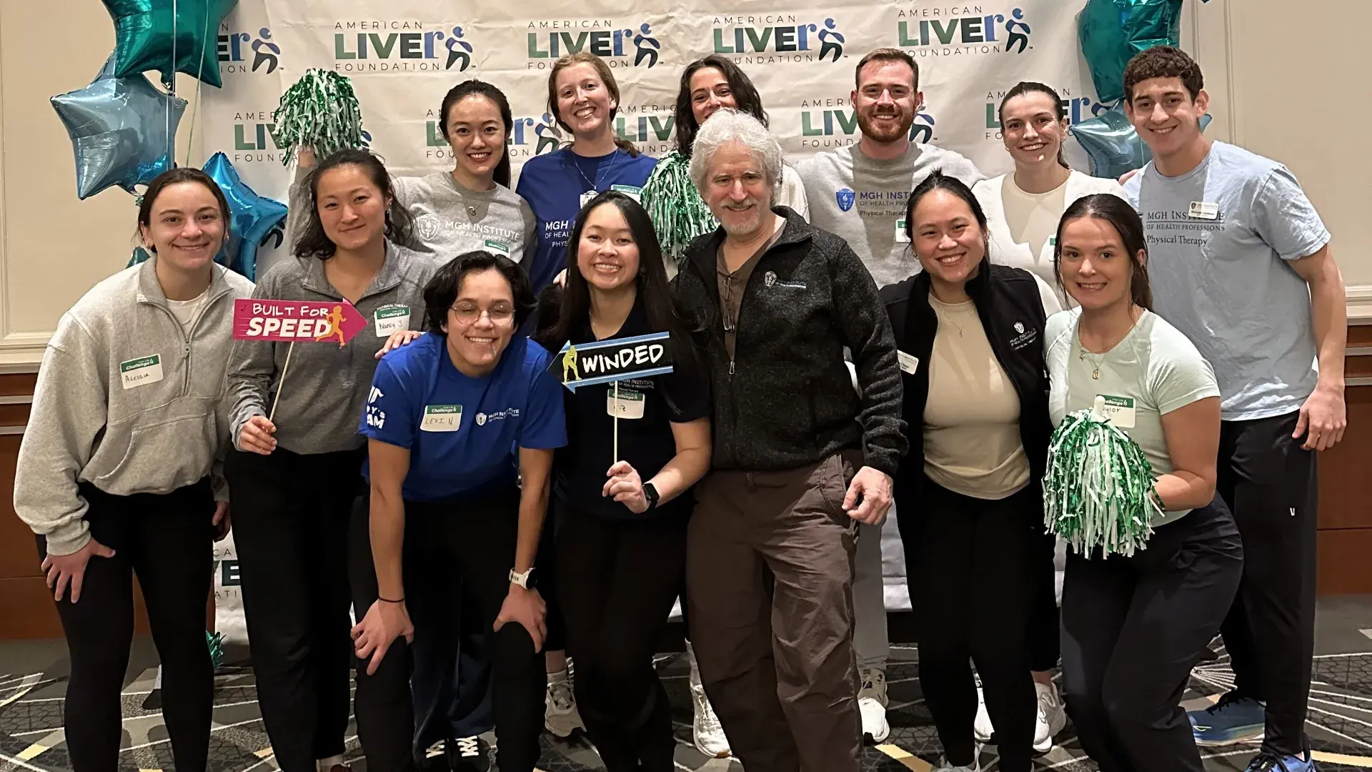 A group of people post in front of a banner