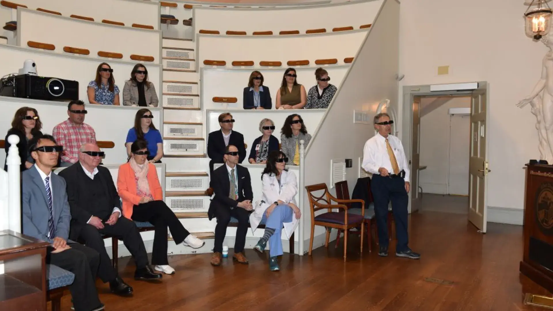 People sit in a classroom wearing dark glasses