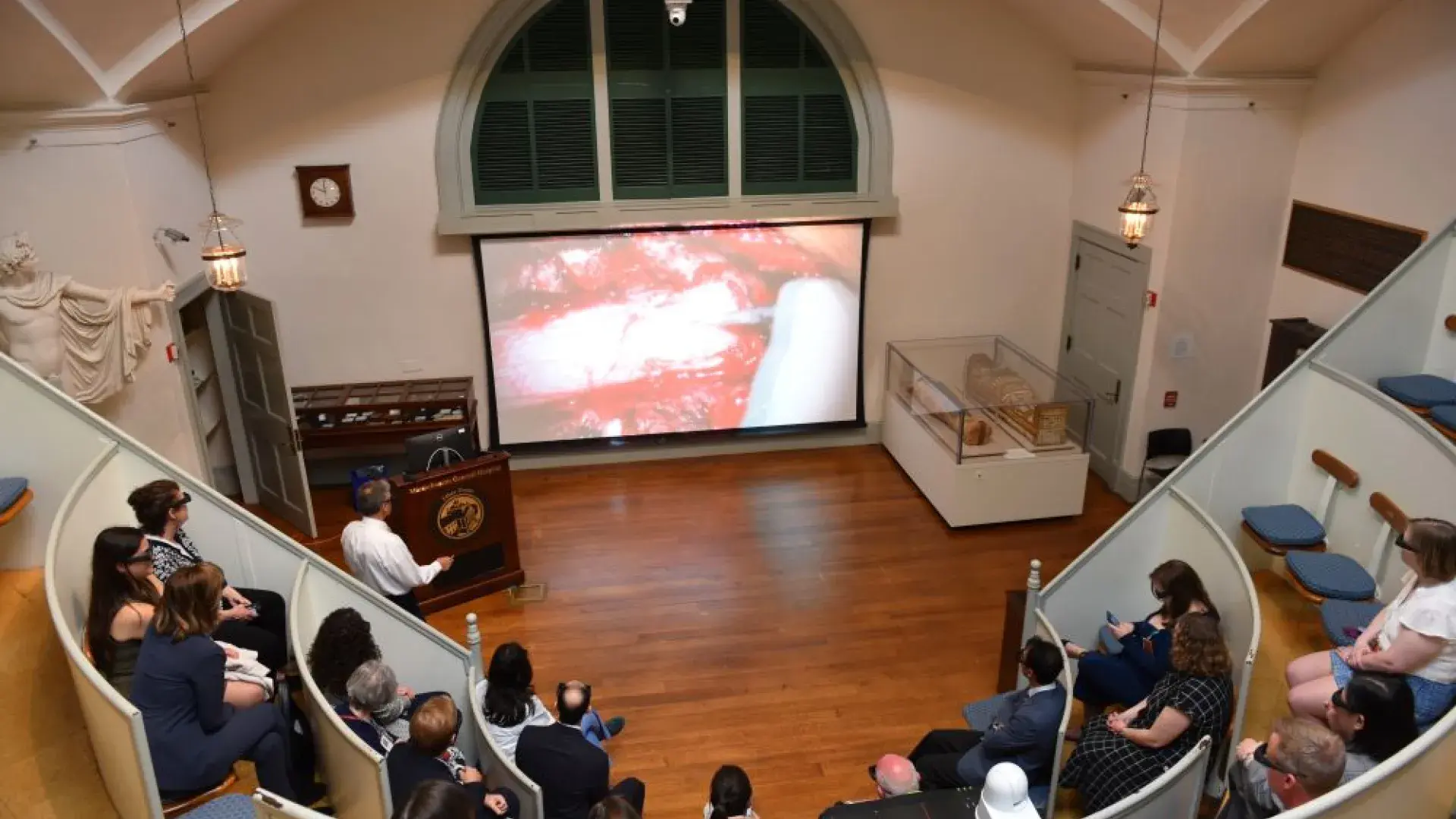 People sit in theater seating to watch a screen
