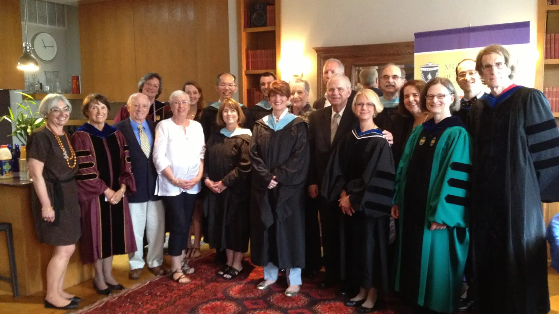 A group of people pose for the camera with several of them wearing graduation gowns