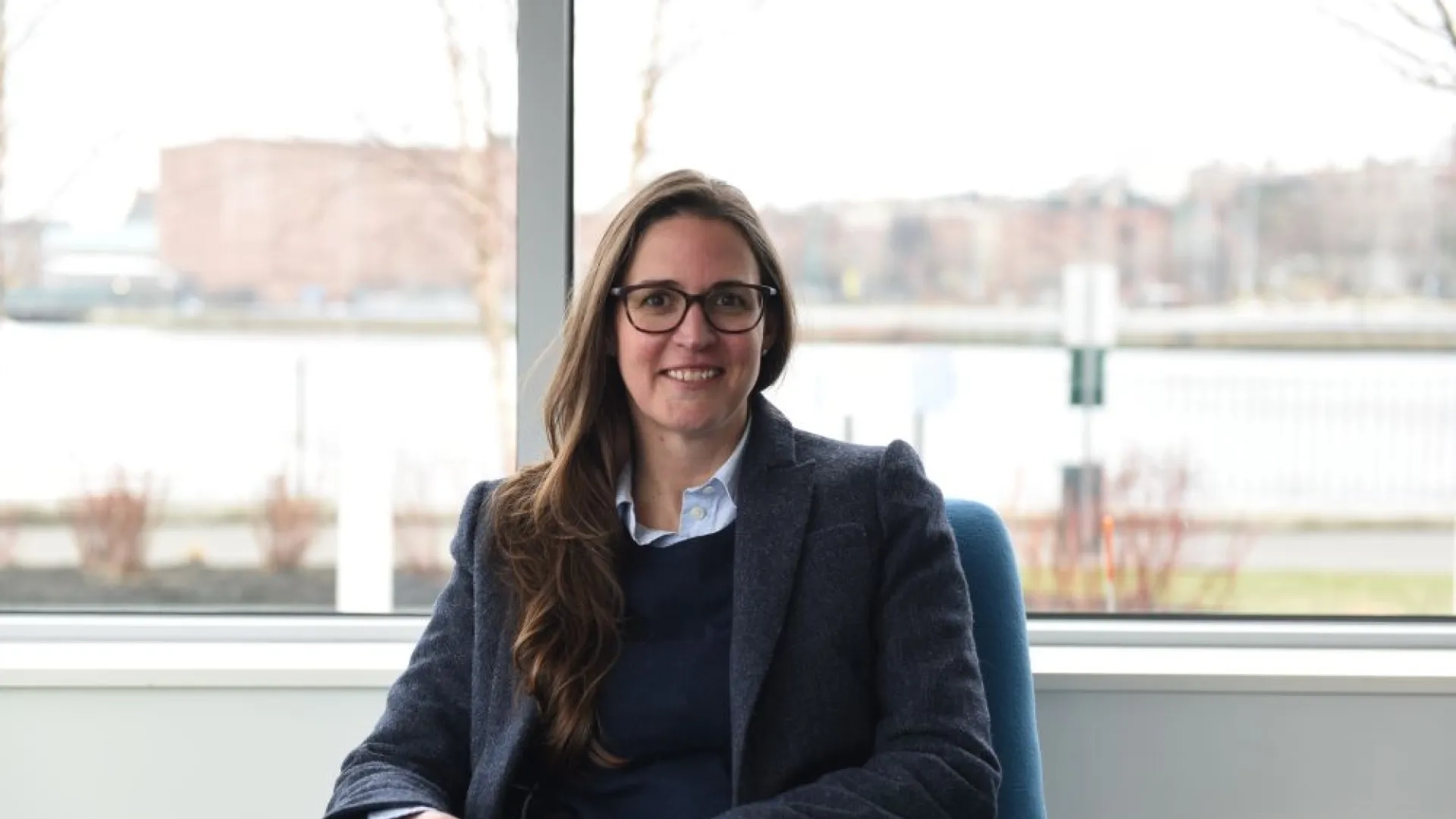 A woman sits in a chair in front of a window
