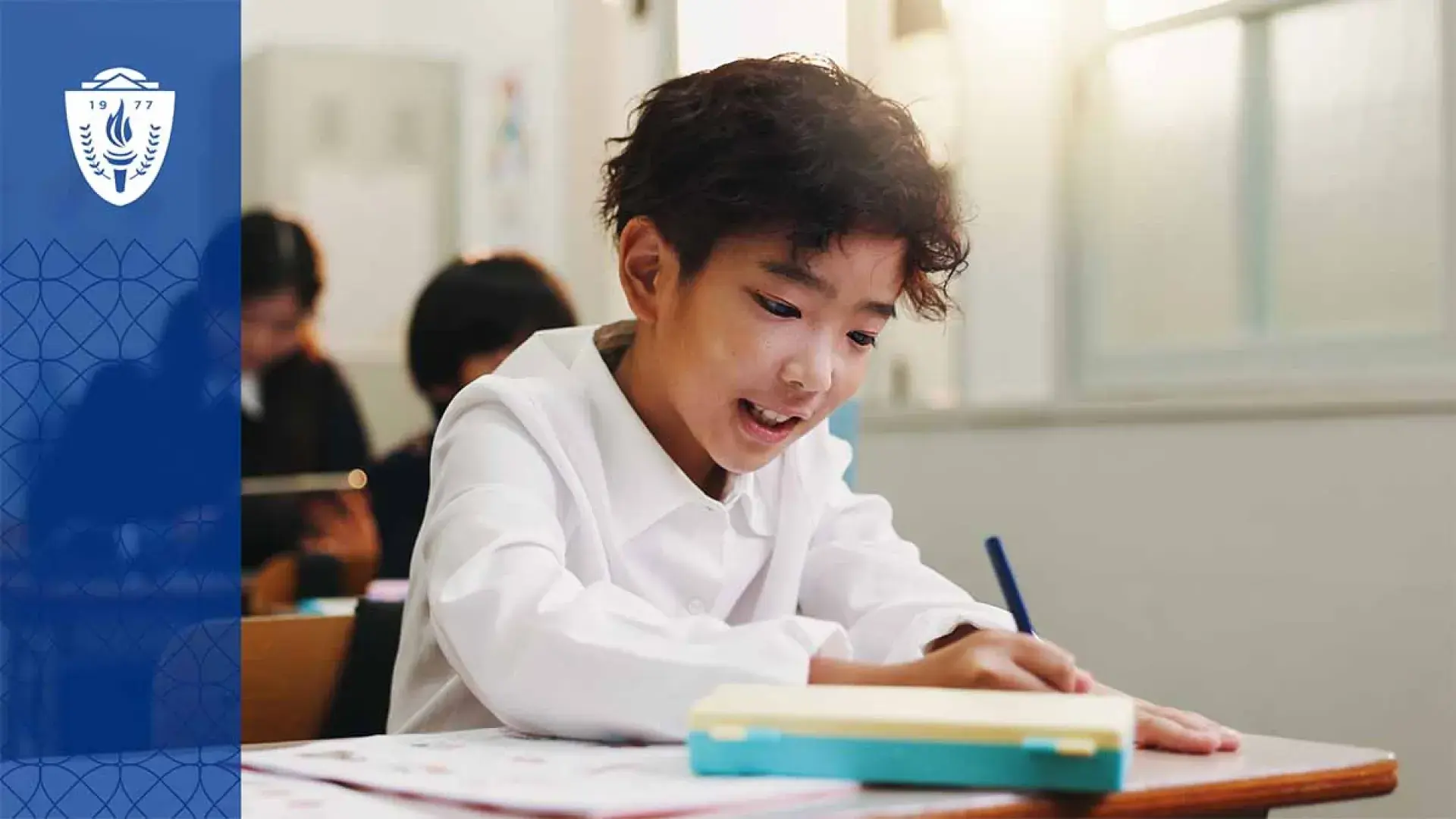 Kid with black hair sitting at desk in school
