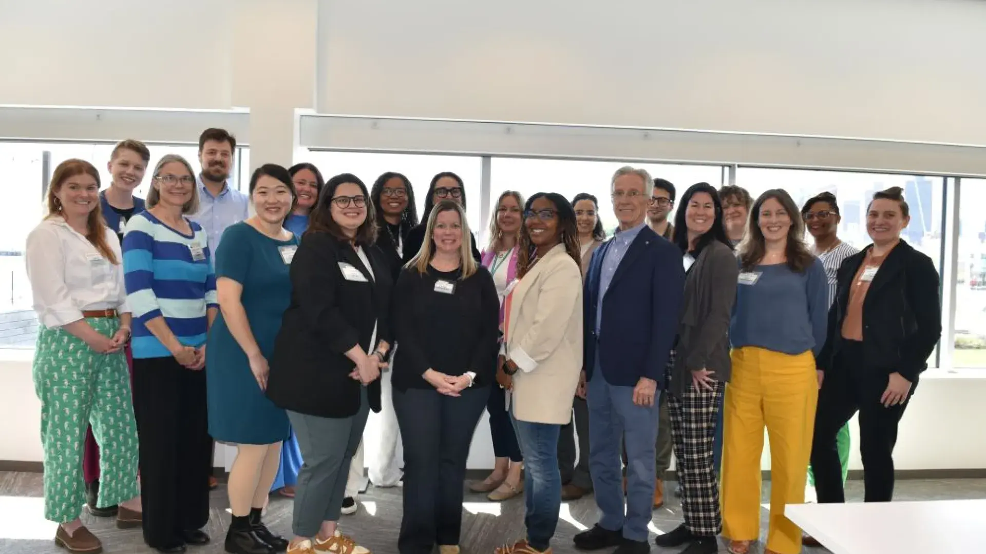 A group of people pose in front of windows