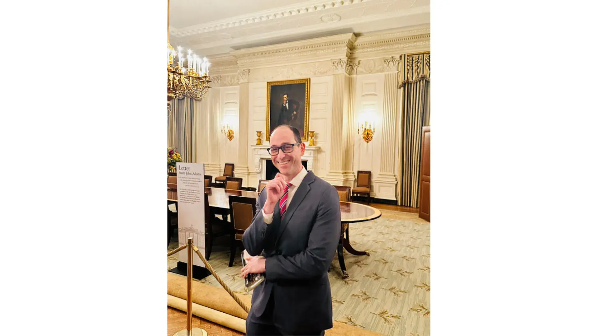 A man stands in front of red ropes that mark a display