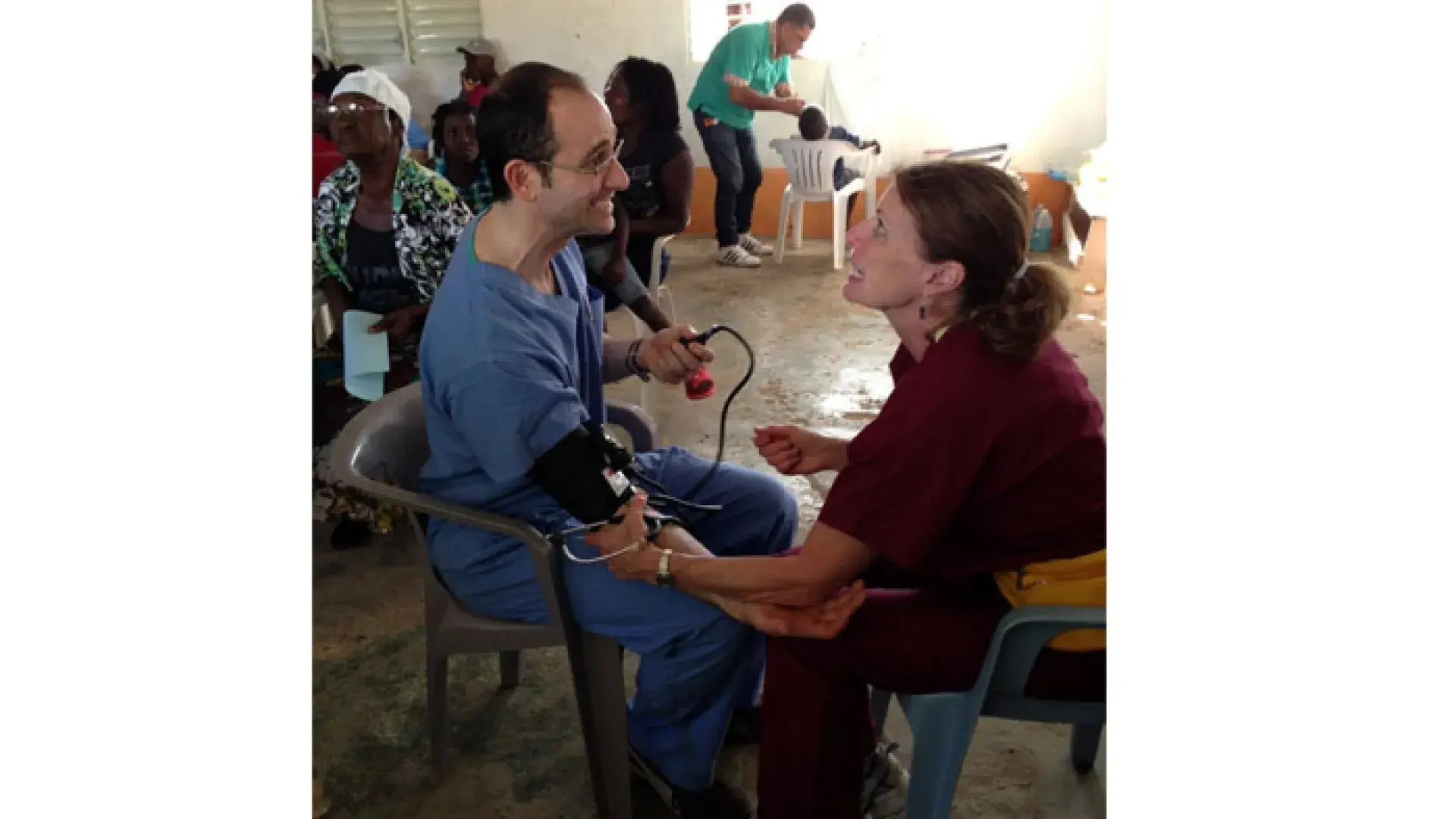 A man with a blood pressure cuff on sits across from a woman holding his arm