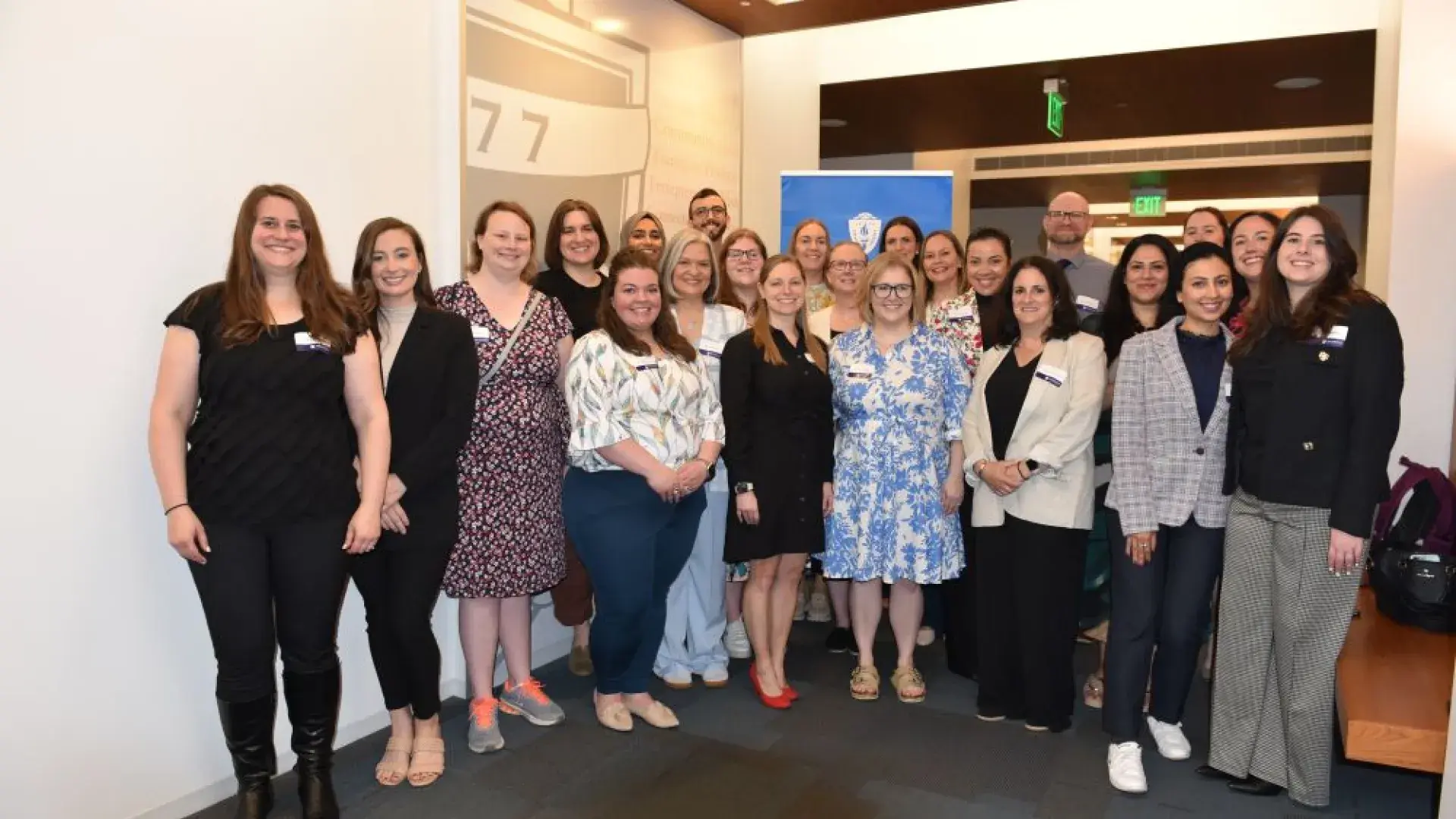 A group of people pose for a photo in front of a wall. 
