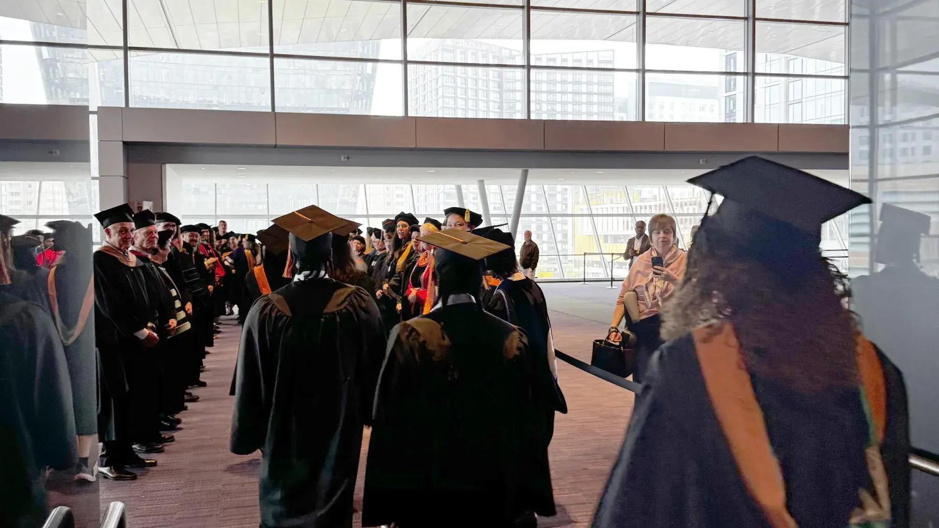 Students walk forward into a tunnel of clapping people. 