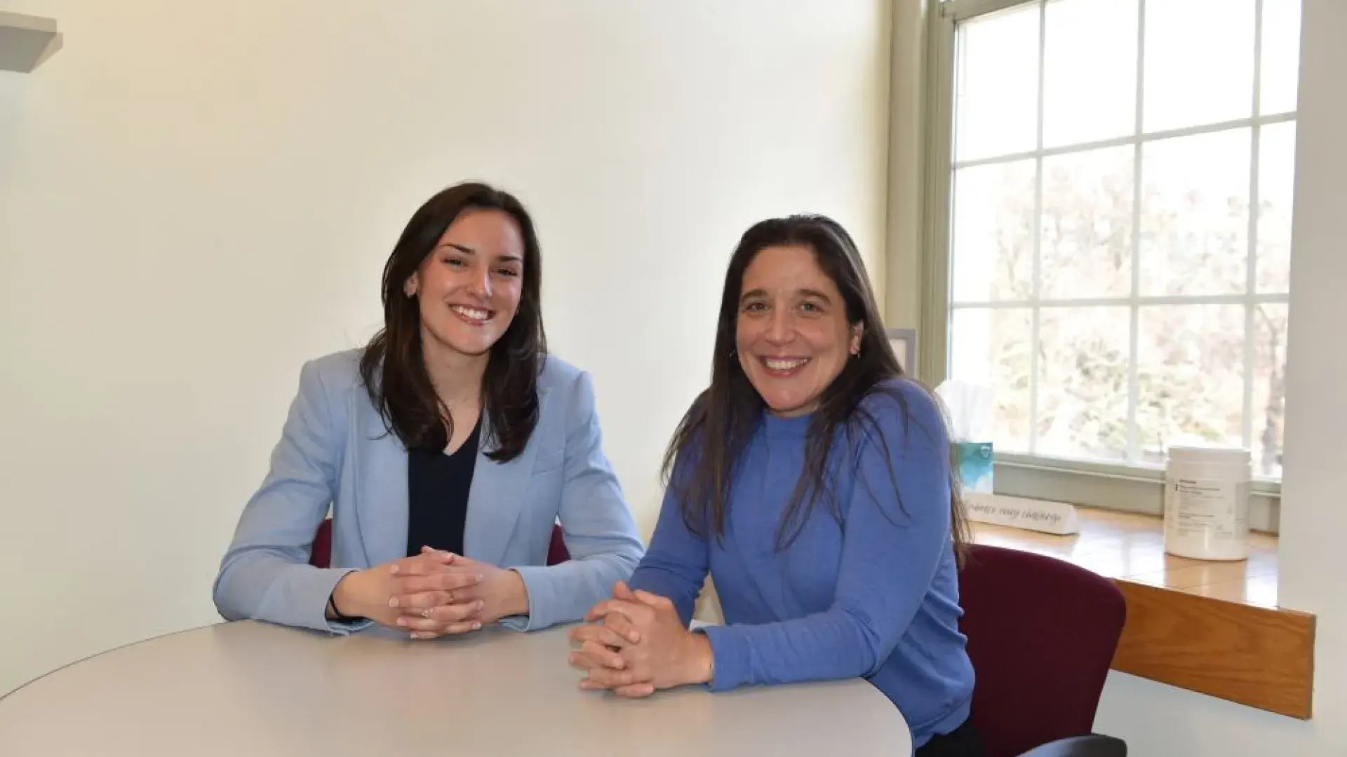 Two women sitting next to each other at a round table