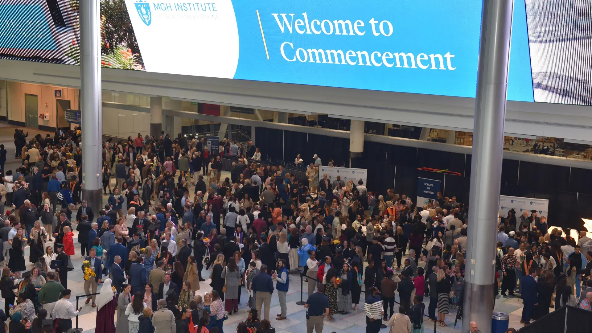 A crowd can be seen from above under a sign that says Welcome to Commencement 