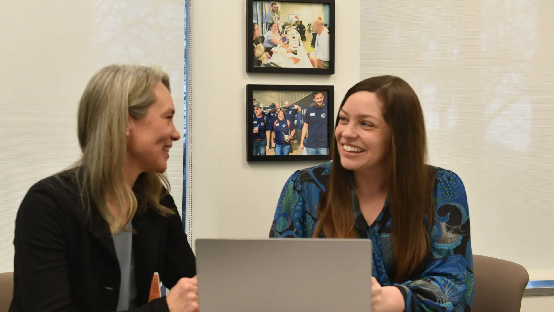 kim and gwen sit at a laptop at a table