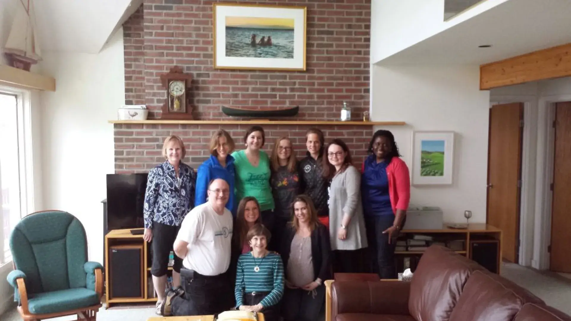A group of people stand in front of a fireplace
