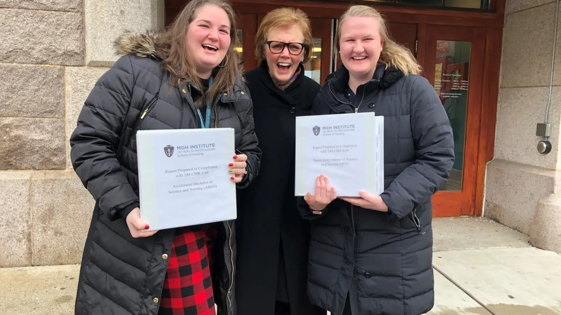 Two women hold certificates while another stands between them