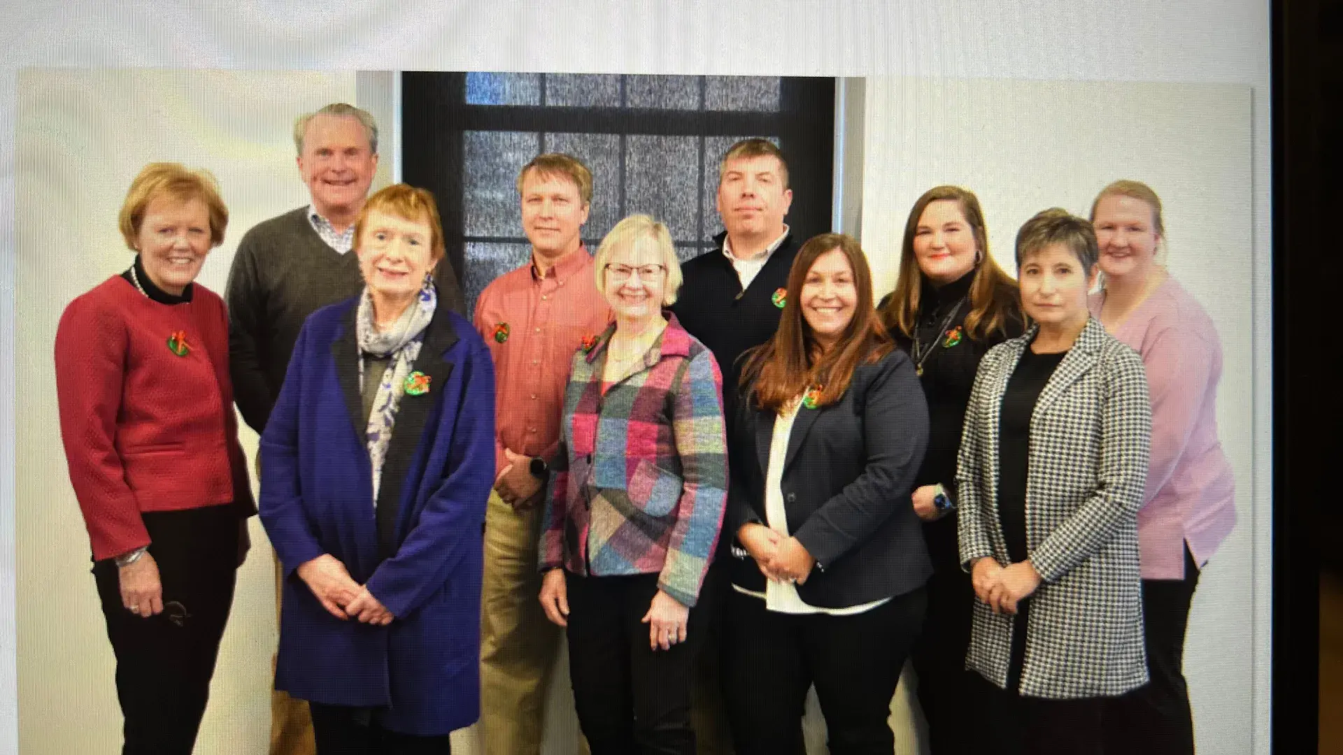 A group of people pose in front of a window