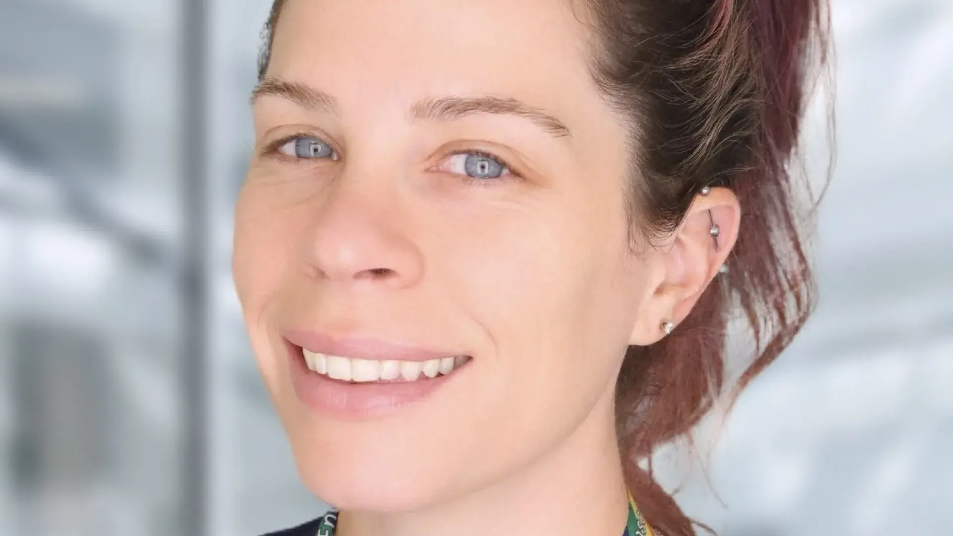 Brenna has a high ponytail and a rainbow lanyard around her neck