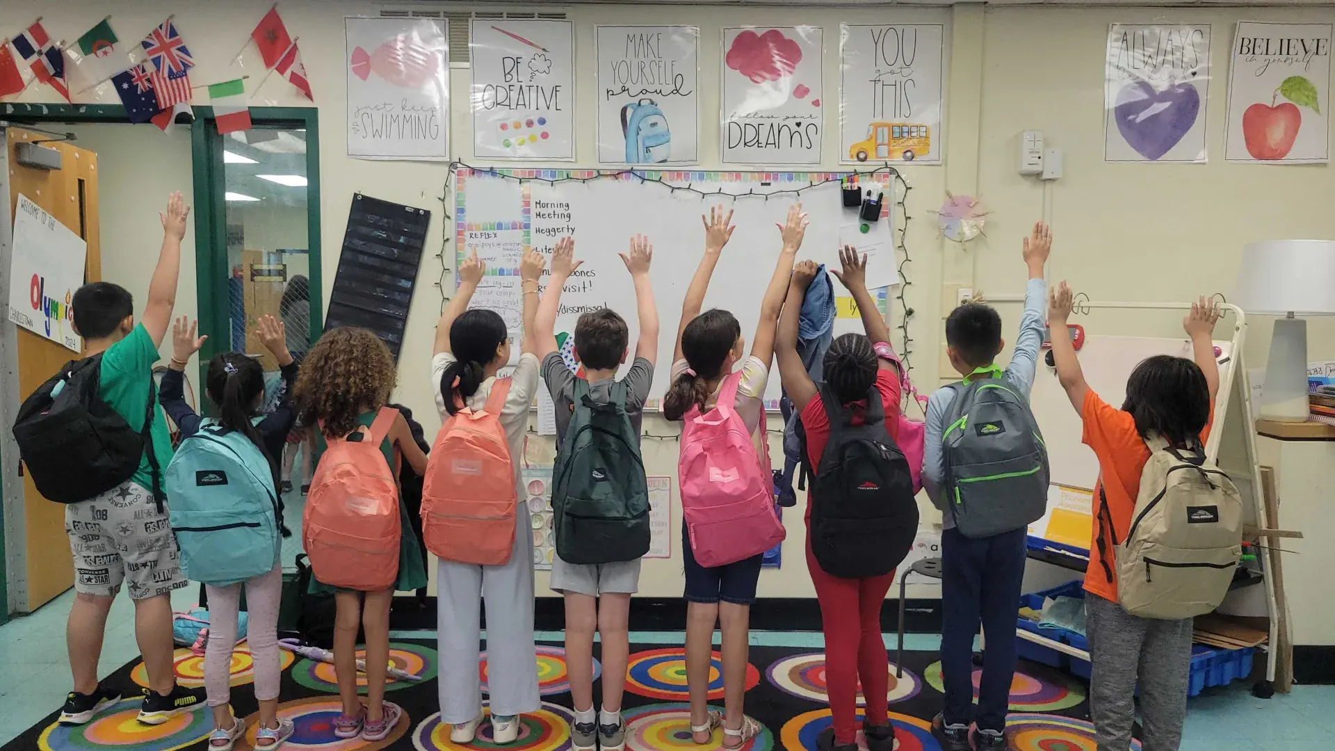 KIds holding hands up with backpack